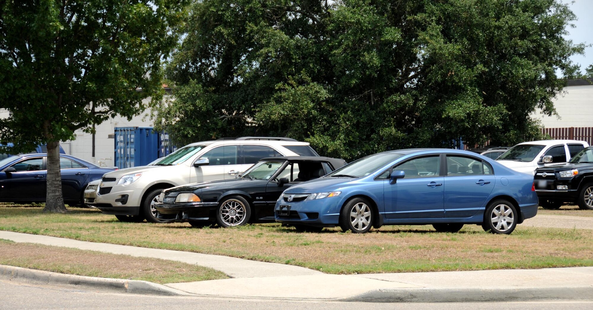 These cars are parked illegally in a grassy area adjacent to Stennis Hall.  (U.S. Air Force photo by Kemberly Groue)