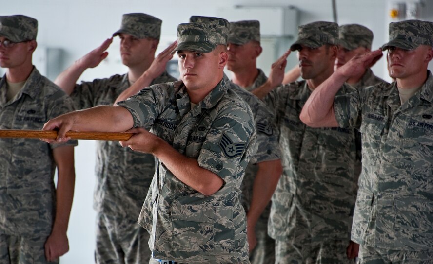 Staff Sgt. Jason Anderson, of the 33rd Maintenance Group, presents the guidon as his fellow maintainers salute during the National Anthem at the MXG’s change of command, July 22 at Eglin Air Force Base, Fla.  (U.S. Air Force photo/Samuel King Jr.)