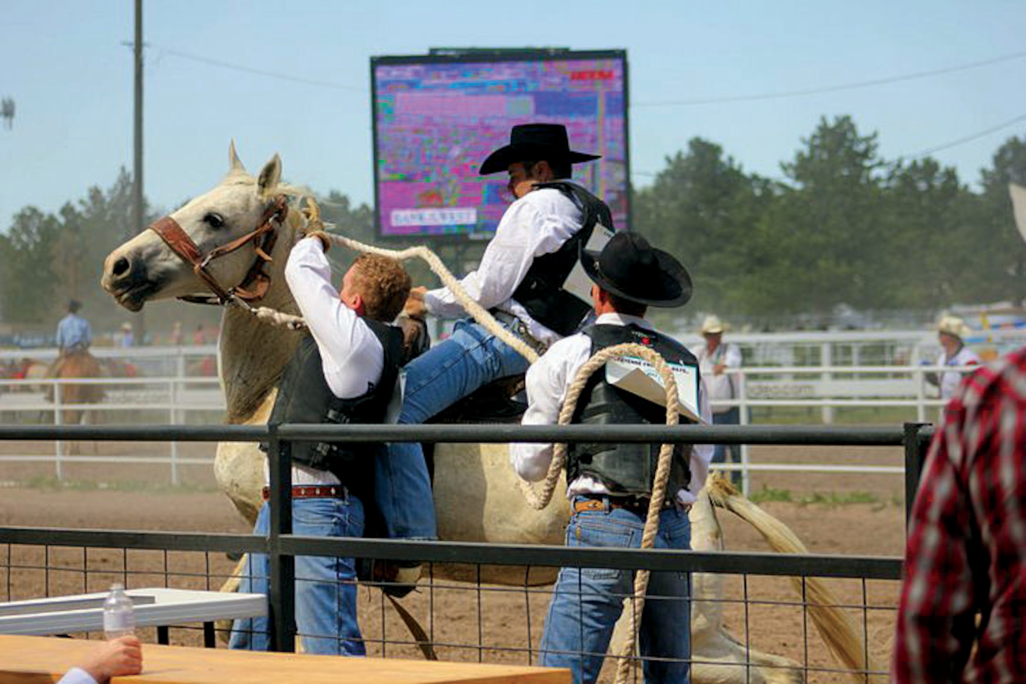 Capt. Carl Barrios, 90th Missile Wing command post senior controller; Capt. Brian Boner, 90th Operations Support Squadron chief of ICBM training scenarios; and Blue Pennington participate in the wild horse race event during the Cheyenne Frontier Days rodeo July 24. (U.S. Air Force photo by Shannon Shin)