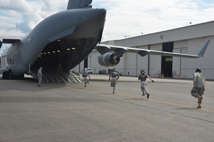 Senior Airman Marvin Richardson, Staff Sgt. Ashley Kelly and Staff Sgt. Luther Franklin race to a C-17 to begin the engine running onload/offload competition July 27 at Joint Base Lewis-McChord, Wash. The aerial porters performed a full onload of an aircraft while the engines were running. The team had 12 minutes to complete the challenge. (U.S. Air Force photo/2nd Lt. Susan Carlson)