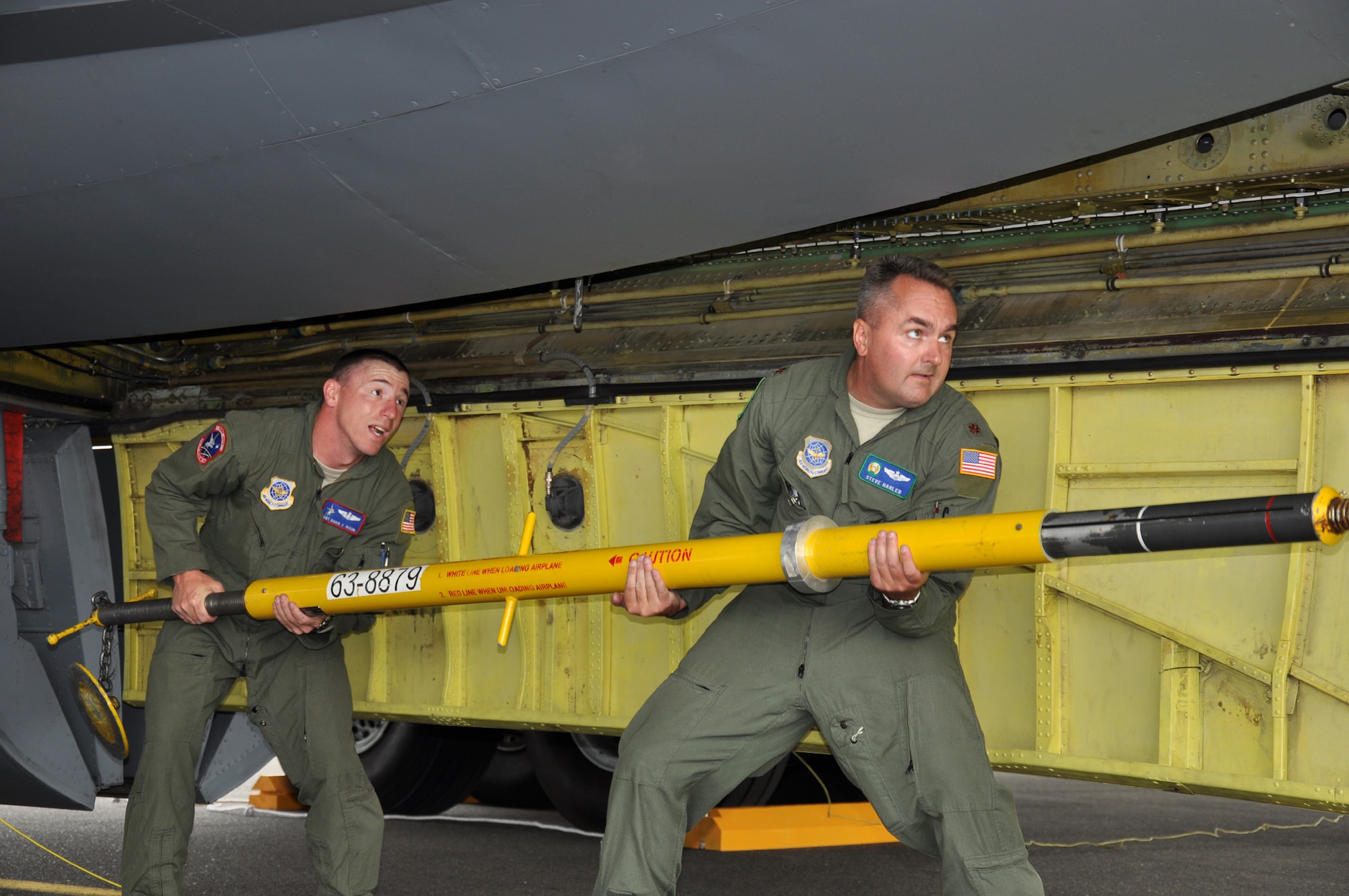 From left, Tech. Sgt. David Nixon and Maj. Steve Harler work to put the tail support strut back in the cargo hold on the underside of the KC-135. The two used quarters to maneuver the screws as the width of the quarter fits perfectly into the spring-loaded screws. (U.S. Air Force Photo/Tech. Sgt. Jennifer Buzanowski)