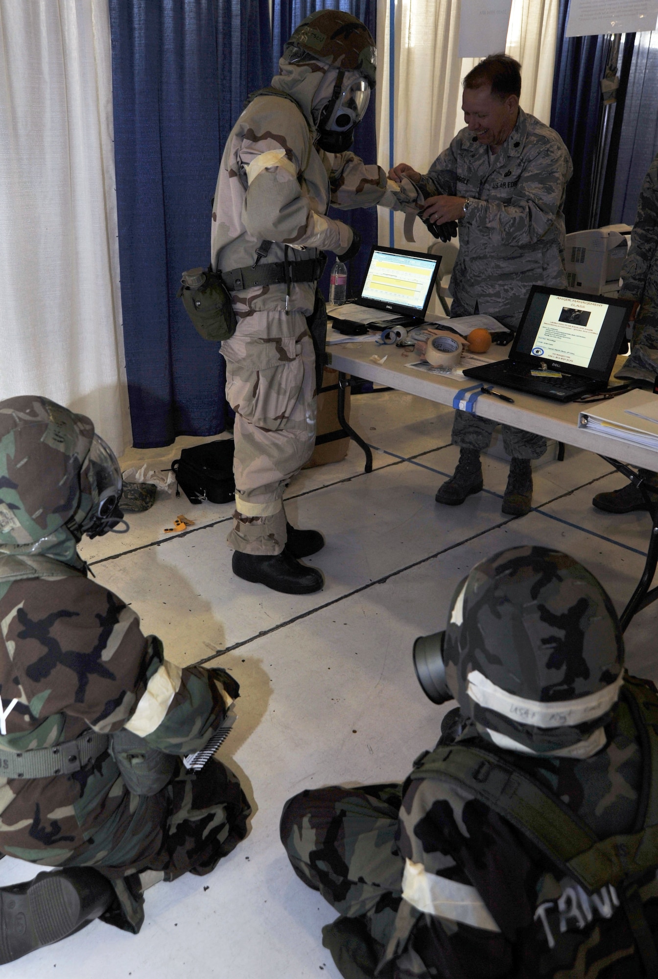 Financial Management Competition members don Mission Oriented Protective Posture gear and stay low during a chemical warfare scenario July 25, 2011, at Joint Base Lewis-McChord, Wash.  The competition was part of Air Mobility Rodeo 2011 and was the first time finance participated in the event.  (U.S. Air Force photo/Senior Airman Abigail Klein)