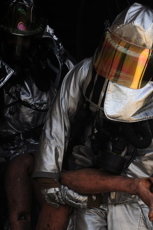 KUNSAN AIR BASE, Republic of Korea -- Firefighters from 8th Civil Engineer Squadron, after extinguishing a fire, pull dummies out of the building here during Exercise Beverly Midnight 11-3 July 28. The new modified Joint Firefighter Integrated Response Ensemble consists of an outer shell to provide liquid protection and a carbon-bead filter material on the inside for vapor protection. (U.S. Air Force photo/Senior Airman Brittany Y. Bateman)
