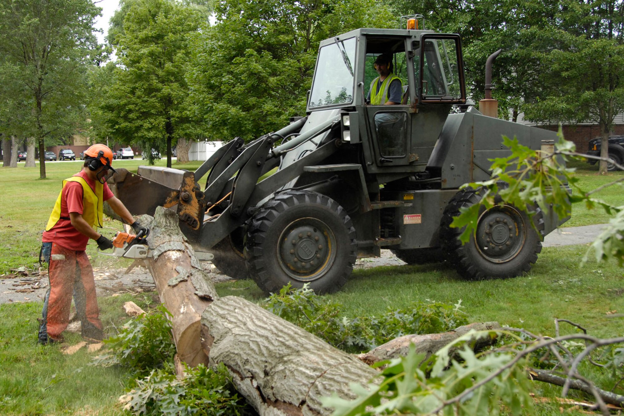 HANSCOM AIR FORCE BASE, Mass. – Nick Banks (with chainsaw) and Steve Morris (operating front loader) work together to remove a tree from behind the Base Chapel. The tree was removed for safety reasons. (U.S. Air Force photo by Linda LaBonte Britt)