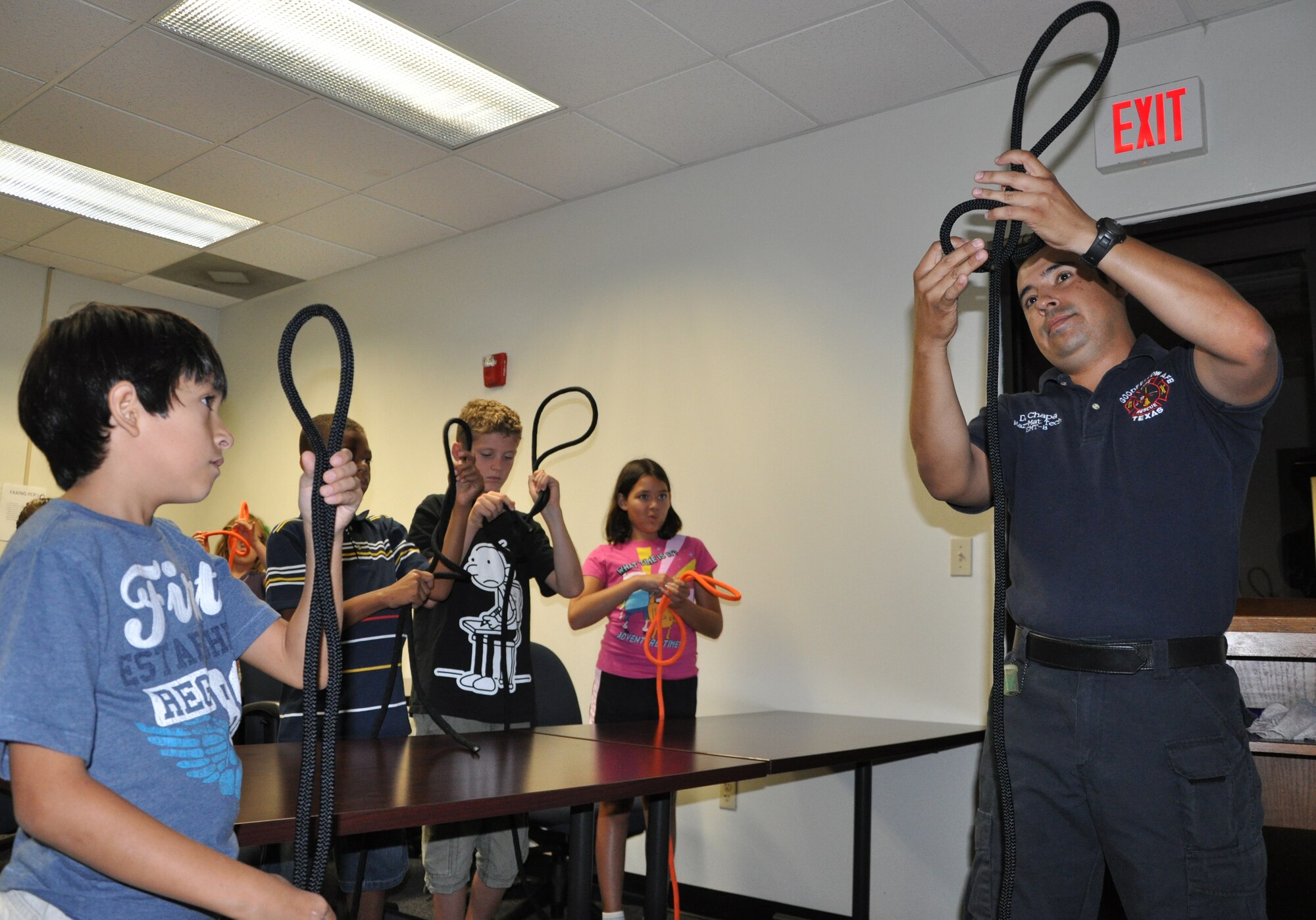 GOODFELLOW AIR FORCE BASE, Texas -- Goodfellow firefighter Miguel Chacon shows Jr. Firefighter Camp participants how to tie a butterfly knot July 26.  Eight youths signed up for the week-long camp and learned basic firefighter skills such as first aid, tying knots, and search and rescue. (U.S.Air Force photo/Senior Airman Tong Duong)