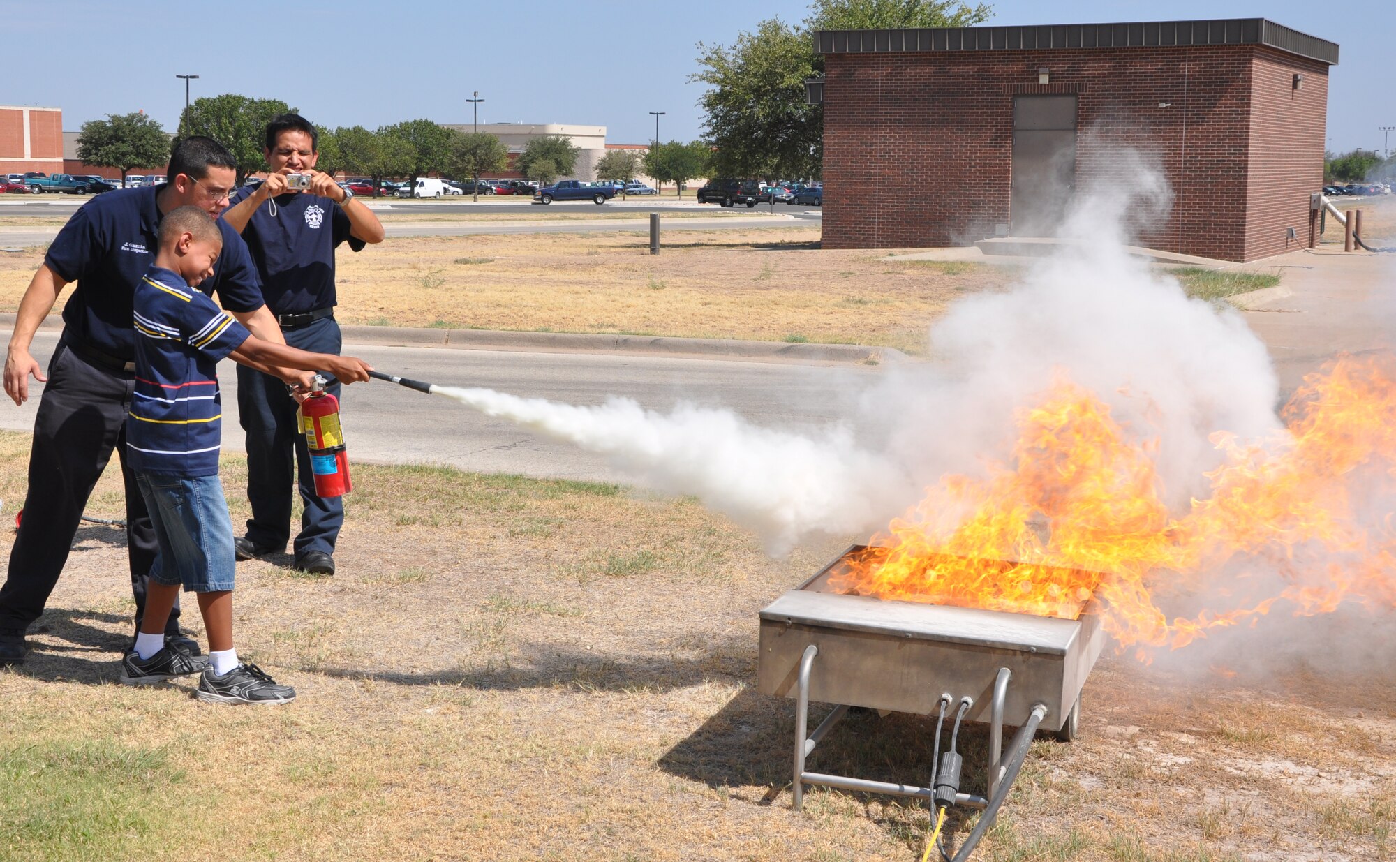 GOODFELLOW AIR FORCE BASE, Texas -- Goodfellow firefighter Jason Garcia, helps Jr. Firefighter Camp participant Chaz Colston how to properly use a fire extinguisher July 26.  Eight youths participated in this year's camp.  (U.S.Air Force photo/Connie Hempel)