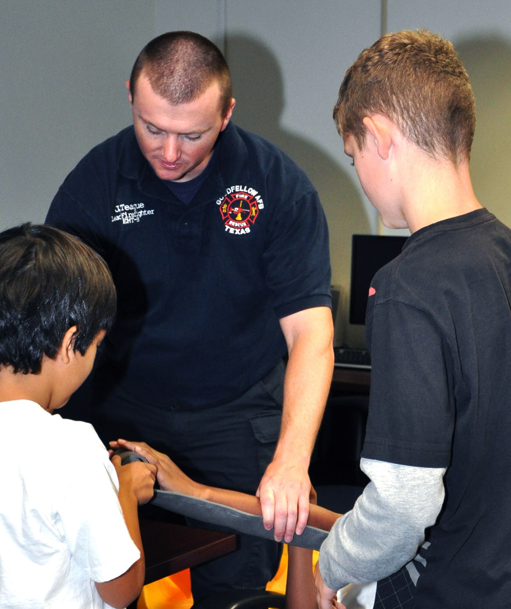 GOODFELLOW AIR FORCE BASE, Texas -- Goodfellow firefighter Jay Teague, shows youths at the Jr. Firefighter Camp how to splint a broken arm during the first aid portion of the week-long camp.  Eight youths participated in this year's camp.  (U.S.Air Force photo/Connie Hempel)