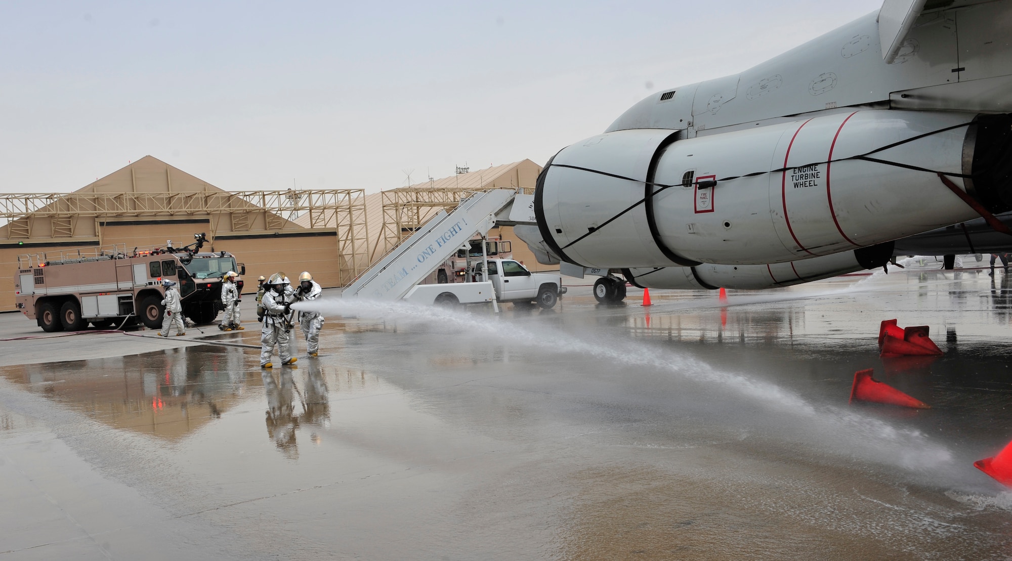 380th Expeditionary Civil Engineer Squadron firefighters spray water toward cones that are simulating fire during an exercise with the French and host nation fire departments, July 26, 2011 at the 380th Air Expeditionary Wing in Southwest Asia. The scenario simulated an auxiliary power unit, or APU, exploding causing a ground fire with nine casualties. (U.S. Air Force photo/Staff Sgt. Patrick Mitchell)