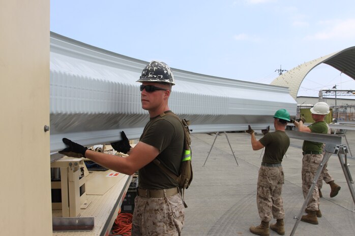 Marine Wing Support Squadron 171 combat engineers guide a piece of steel out of the Ultimate Building Machine during a UBM K-span training evolution at the MWSS-171 combat engineer lot here July 28. This is the final transformation before the steel moves to the assembly phase.