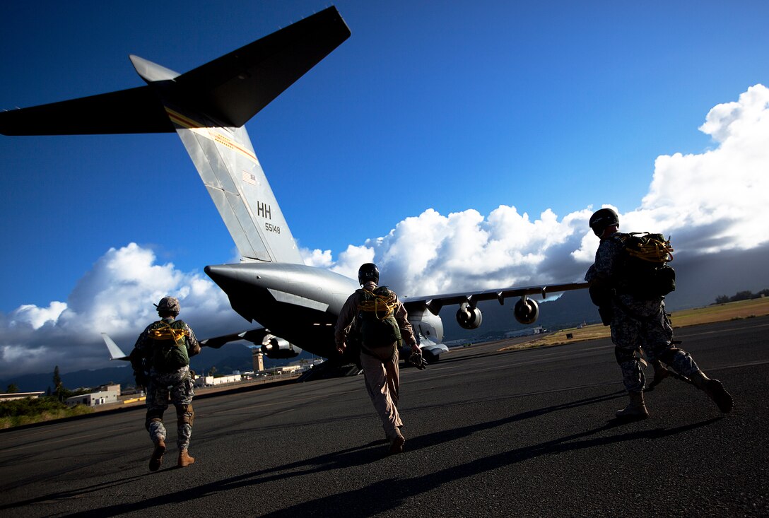 Sgt. Brian Zygmant, a parachute rigger with 4th Force Reconnaissance Company, 4th Marine Division, and soldiers with Special Operations Command, Pacific, walk toward an Air Force C-17 transport aircraft before parachuting over Marine Corps Base Hawaii, July 28, 2011. Over a two-day training event, the recon Marines combined forces with Army, Air Force and Navy parachutists from SOCPAC and SEAL Delivery Vehicle Team 1 to conduct static-line and free-fall parachute operations. Conducted bi-monthly as part of the recon Marines’ sustainment training, the parachute operations served to better parachutist jump proficiency, and allowed jumpmasters to gain experience supervising their parachutists.