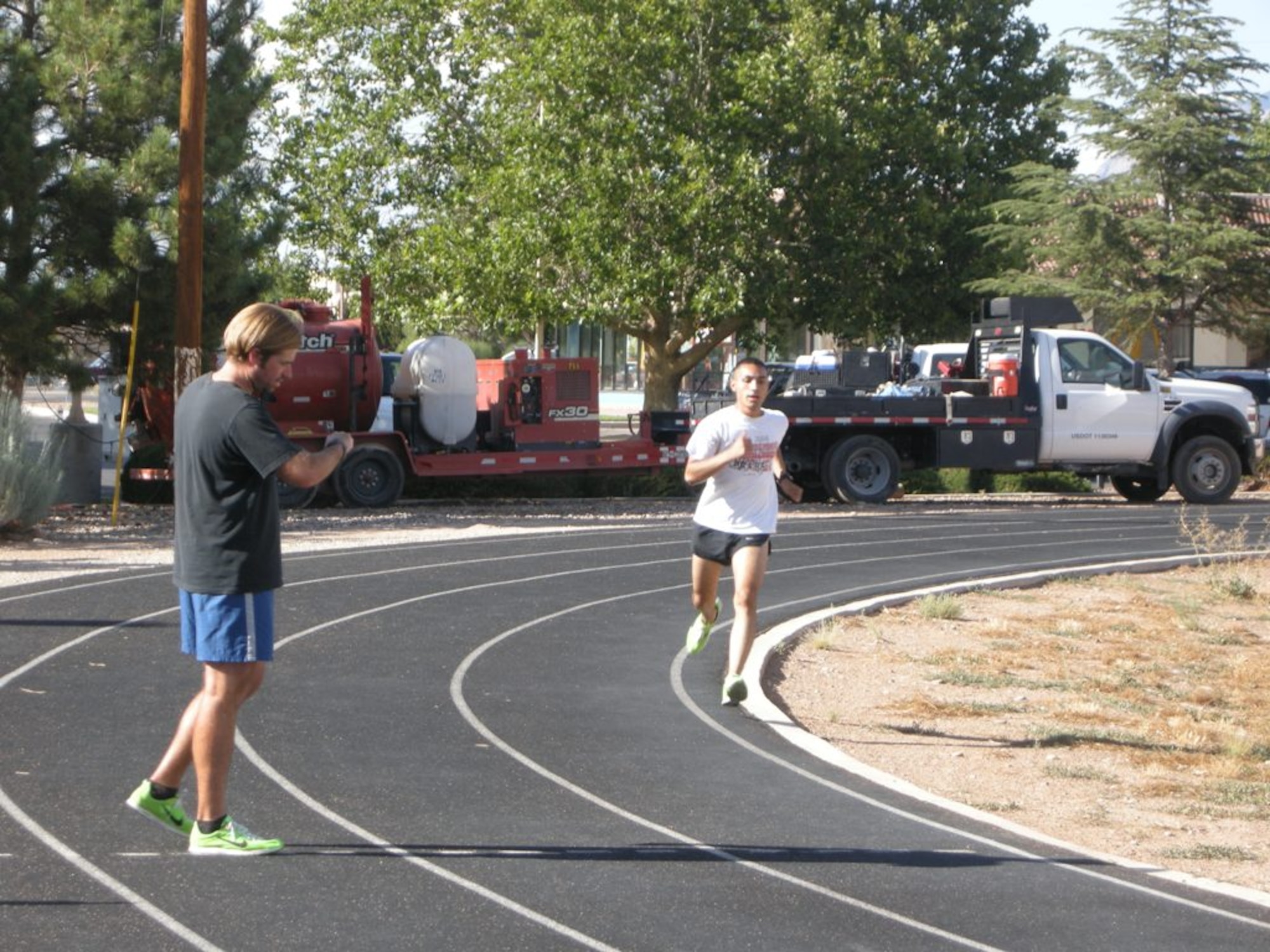Zac Holmes, left, a fitness assessment cell specialist at Kirtland Air Force Base, checks the running pace of Airman 1st Class Monte Murillo, 550th Aircraft Maintenance Unit, during a recent time trial at the Roadrunner Track. Murrillo and Airman 1st Class Joseph J. Medley, 58th Maintenance Operations Squadron, were selected for the Air Force Materiel Command men’s half-marathon team.

Photo by John Cochran