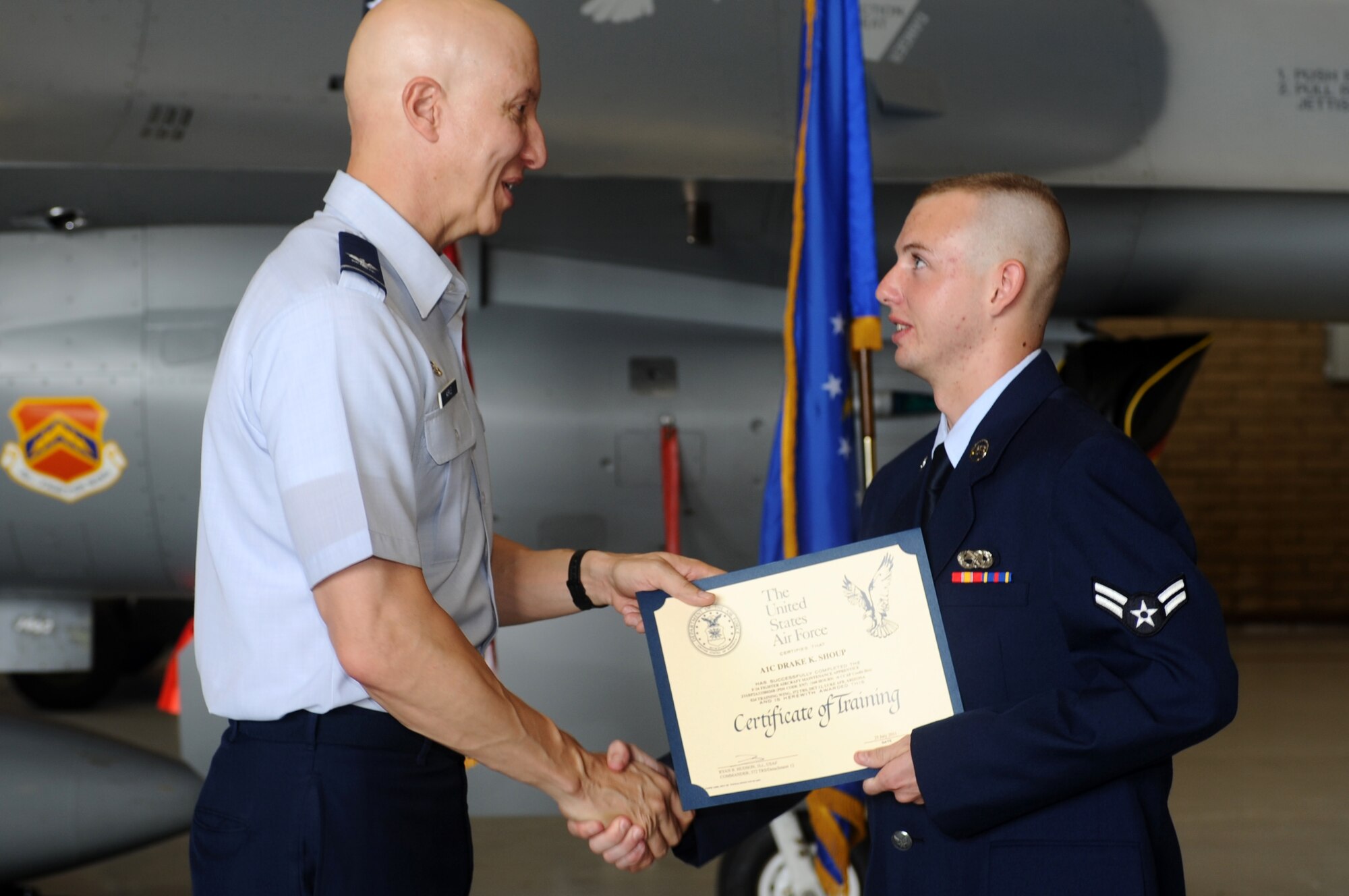 Col. Perter Markle, 982nd Training Group commander, Sheppard Air Force Base, Texas, presents Airman 1st Class Drake Shoup, the 10,000th Mission Ready Airman graduate from the Detachment 12, 372nd Training Squadron, with a training certificate July 25 during the MRA graduation ceremony held in Hangar 485, Luke Air Force Base, Ariz.  (U.S. Air Force photo by Senior Airman Tracie Forte)