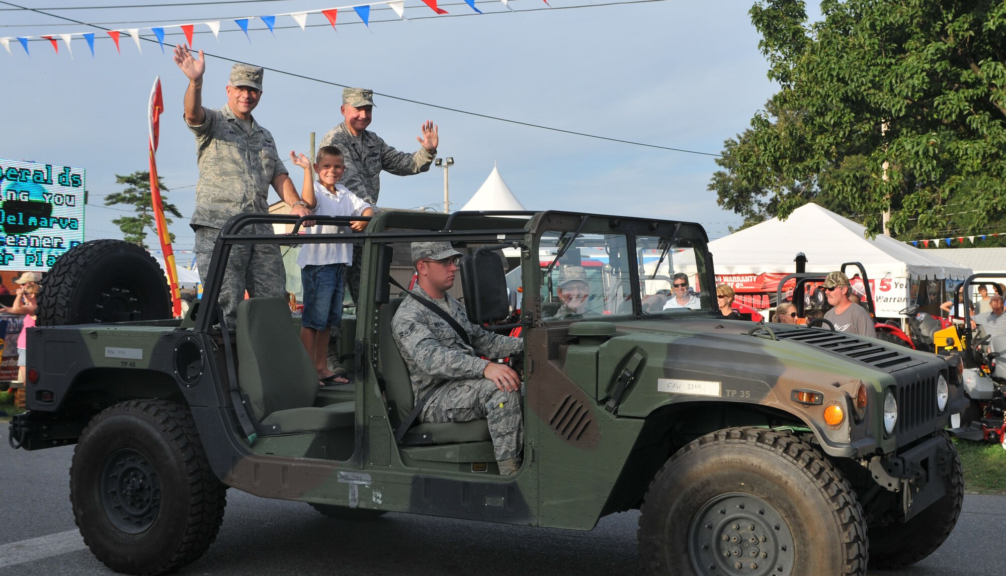 Col. Randal L. Bright, (left), the commander of the 512th Airlift Wing, his son, Garrett, and Col. Cal Mercer, the vice commander of the 436 AW, wave to the crowd during the Delaware State Fair parade July 27, 2011, at Harrington, Del. The parade featured floats, antique tractors and the 287th Army Marching Band. In recognition of Armed Forces Day, military members received free admission to the fair. (U.S. Air Force photo by Capt. Marnee A.C. Losurdo)