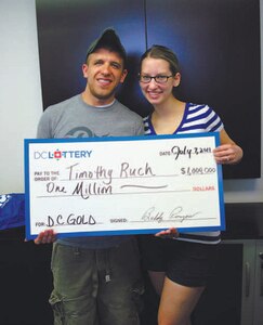 Staff Sgt. Timothy Ruch, 11th Wing Command Post Status of Resources and Training System manager, and Senior Airman Emily Ruch, 11th WG/CP senior controller, accept a check for $1 million after winning on a $20 scratch ticket during a baseball game July 5 at Nationals Park.  (Courtesy Photo)