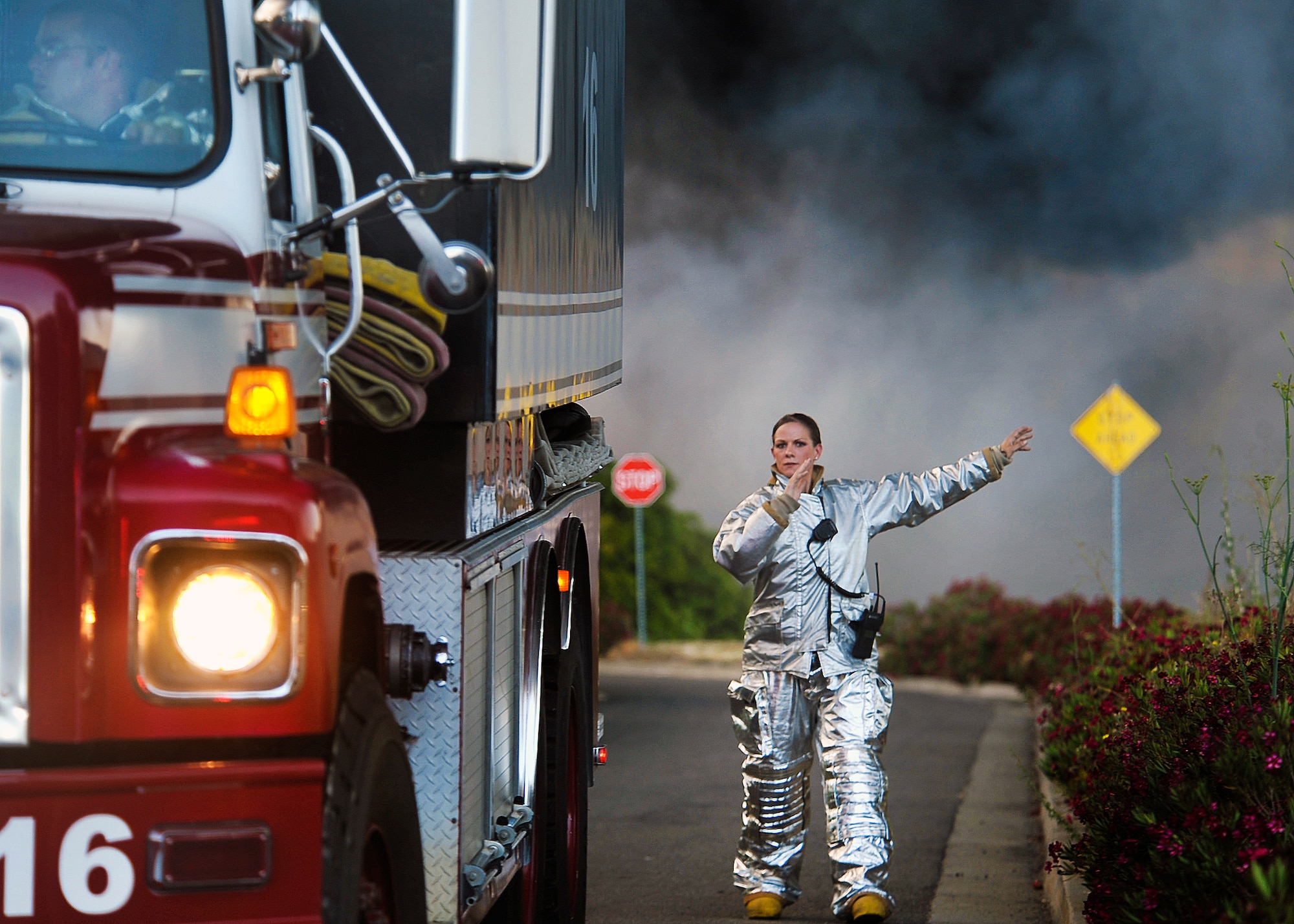 Senior Airman Sherice Lovato marshalls a fire truck into position Tuesday when Travis assisted the Fairfield Fire Department as it battled a fire at a plastics company near the base. The blaze broke out at approximately 1:30 p.m. (U.S. Air Force photo/T.C. Perkins)
