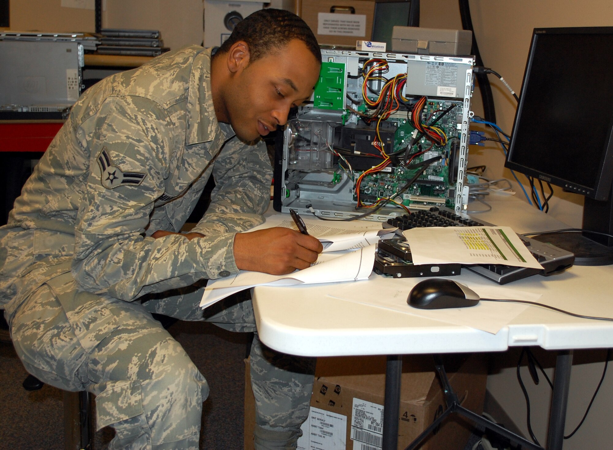 Airman 1st Class Andreas Shiver, a 341st Communications Squadron Visual Imagery Intrusion Detection technician, fills out some paperwork July 25 that is required for migrating computers to the AFNet system. Shiver is helping get the nearly 4,500 computers on base ready for the upcoming conversion. (U.S. Air Force photo/Valerie Mullett)