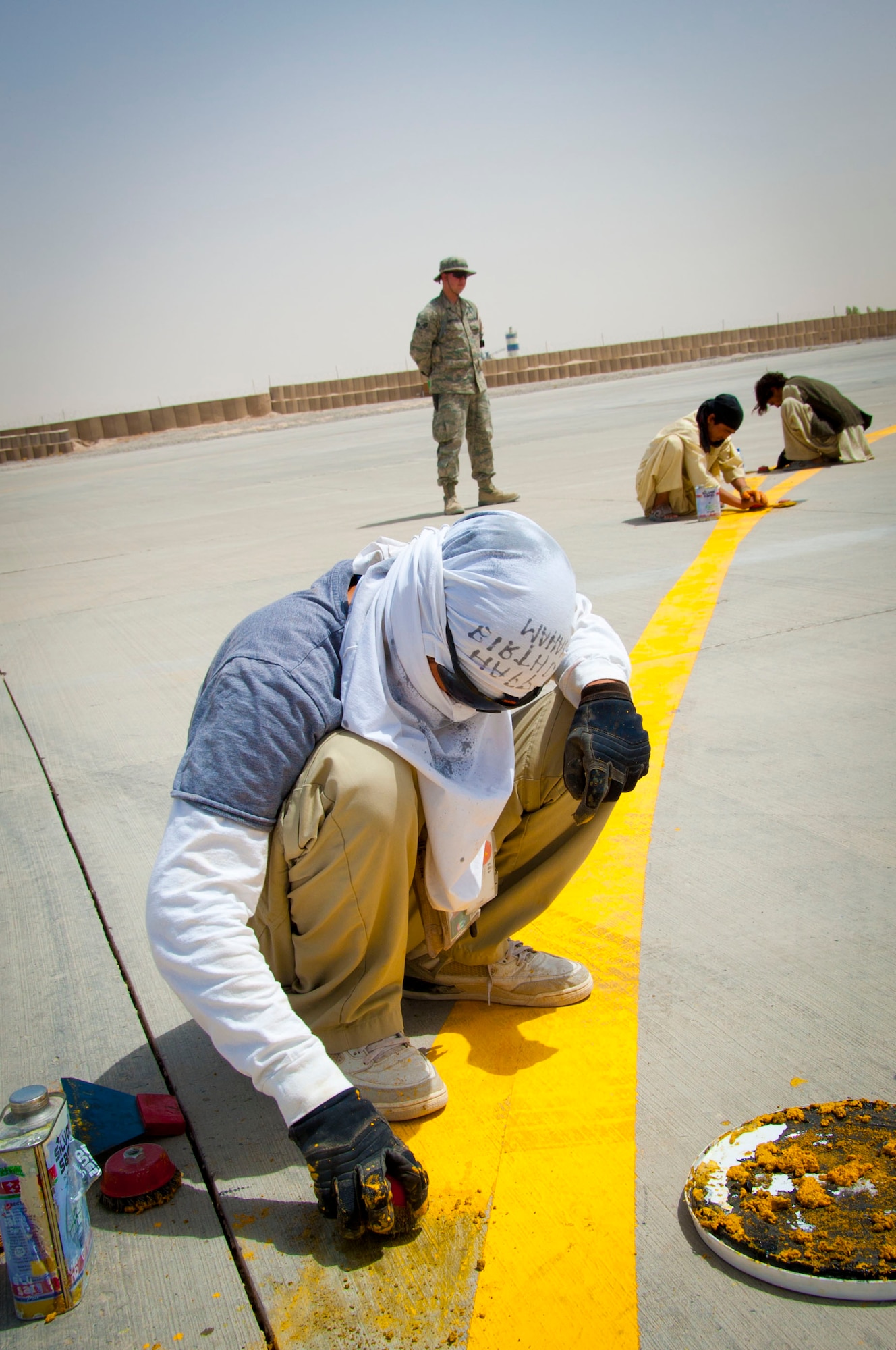 Senior Airman Kenneth Henderson, 451st Expeditionary Civil Engineer Squadron force protection augmentee, supervises Afghan workers at Kandahar Air Field, Afghanistan, July 28, 2011. Many Afghans support coalition forces at Kandahar Air Field by working as contractors. (U.S. Air Force photo by Senior Airman Corey Hook)