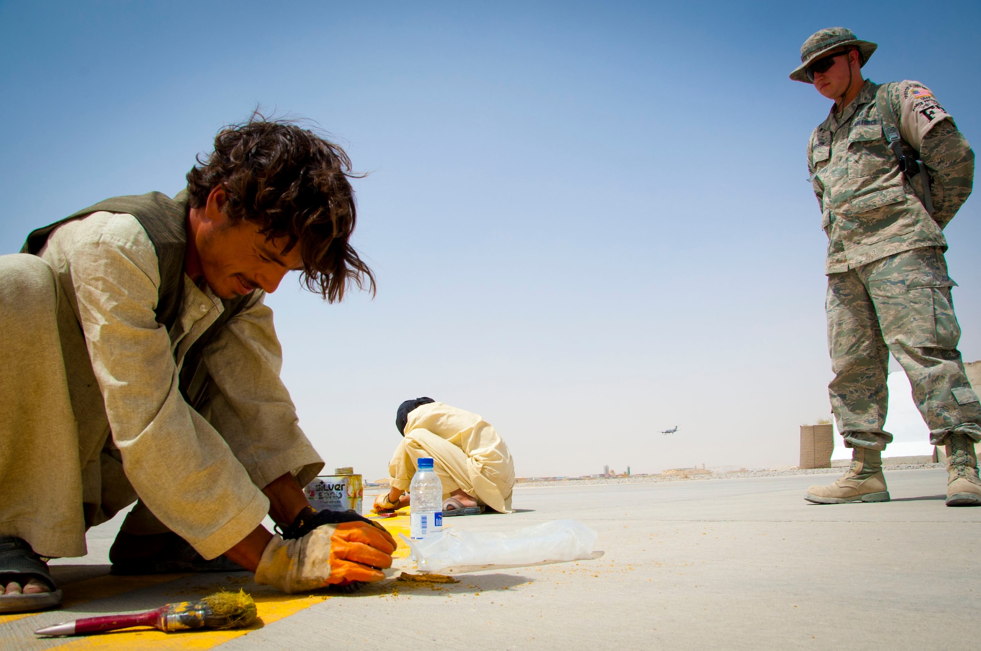 Senior Airman Kenneth Henderson, 451st Expeditionary Civil Engineer Squadron force protection augmentee, supervises Afghan workers at Kandahar Air Field, Afghanistan, July 28, 2011. Many Afghans support coalition forces at Kandahar Air Field by working as contractors. (U.S. Air Force photo by Senior Airman Corey Hook)