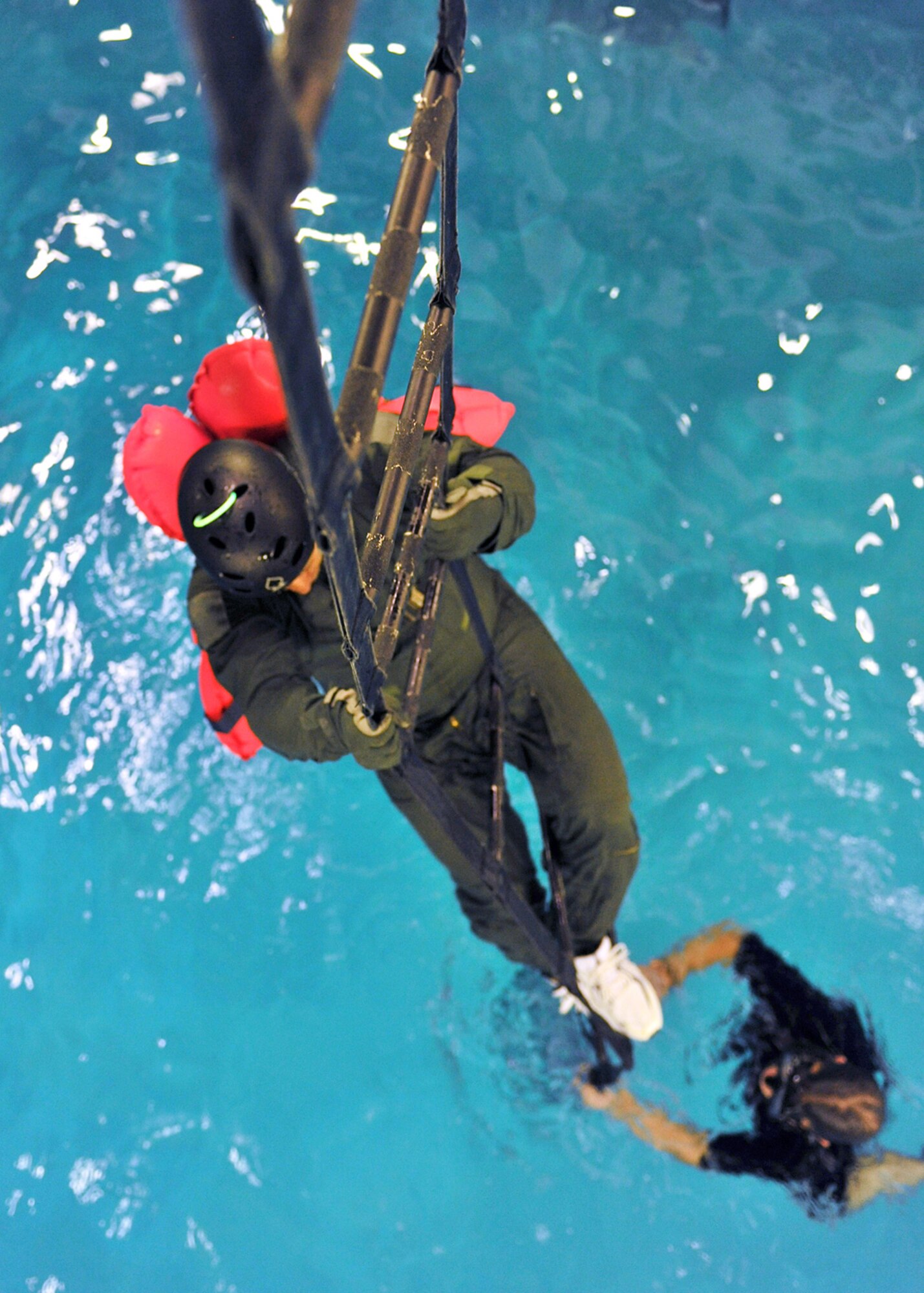 LOWESTOFT COLLEGE, England -- A U.S. Air Force aircrew member pulls himself up a ladder, held down by a survival, evasion, resistance and escape instructor, during water survival training July 14, 2011. Airmen from RAFs Mildenhall and Lakenheath underwent the training which was held in the half-Olympic size pool, and replicated horrific sea conditions. The training, conducted 12 times a year, is extremely important, as it can mean the difference between life and death. (U.S. Air Force photo/Staff Sgt. Tabitha Lee)
