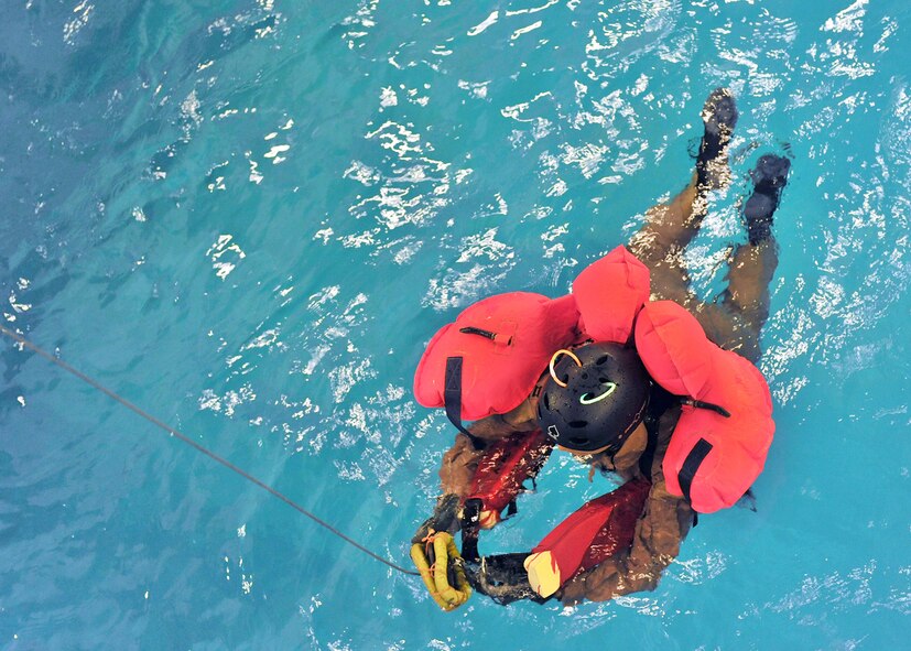 LOWESTOFT COLLEGE, England -- Karen Abeyasekere, 100th Air Refueling Wing Public Affairs, hooks herself up to the harness on a winch, similiar to that on a helicopter, aided by Master Sgt. Matt Ruch (not pictured), 100th Operations Squadron survival, evasion, resistance and escape operations and training superintendent and SERE instructor, to ensure she has the harness on securely and safely. Abeyasekere, along with 12 U.S. Air Force members from RAFs Mildenhall and Lakenheath, participated in the water survival training July 14, 2011. All aircrew have to undergo this training, which provides them the practical experience and helps them gain confidence to know what to do in a real-world situation. The public affairs specialist participated in the training as part of her "Karen A. picks up the gauntlet" series of articles, which give a first-hand account of the things our Airmen do daily, and highlights those jobs which people may not otherwise know about.  (U.S. Air Force photo/Staff Sgt. Tabitha Lee)