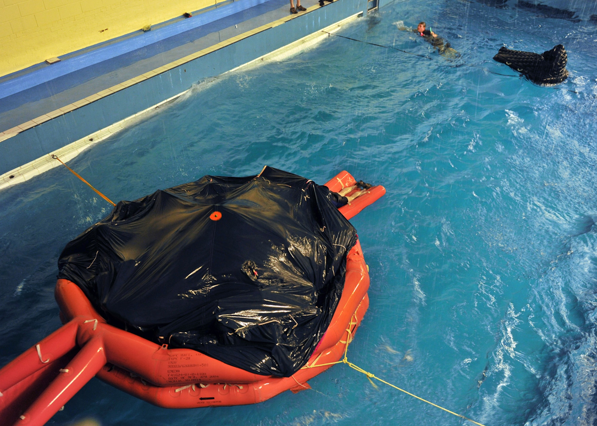 LOWESTOFT COLLEGE, England -- At the 16-feet deep pool, harsh waves start to calm as U.S. Air Force members from RAFs Mildenhall and Lakenheath huddle under cover in a life raft, drenched after swimming over the raft and climbing inside July 14, 2011. This was part of the survival, evasion, resistance and escape training which aircrew have to periodically go through. (U.S. Air Force photo/Staff Sgt. Tabitha Lee)