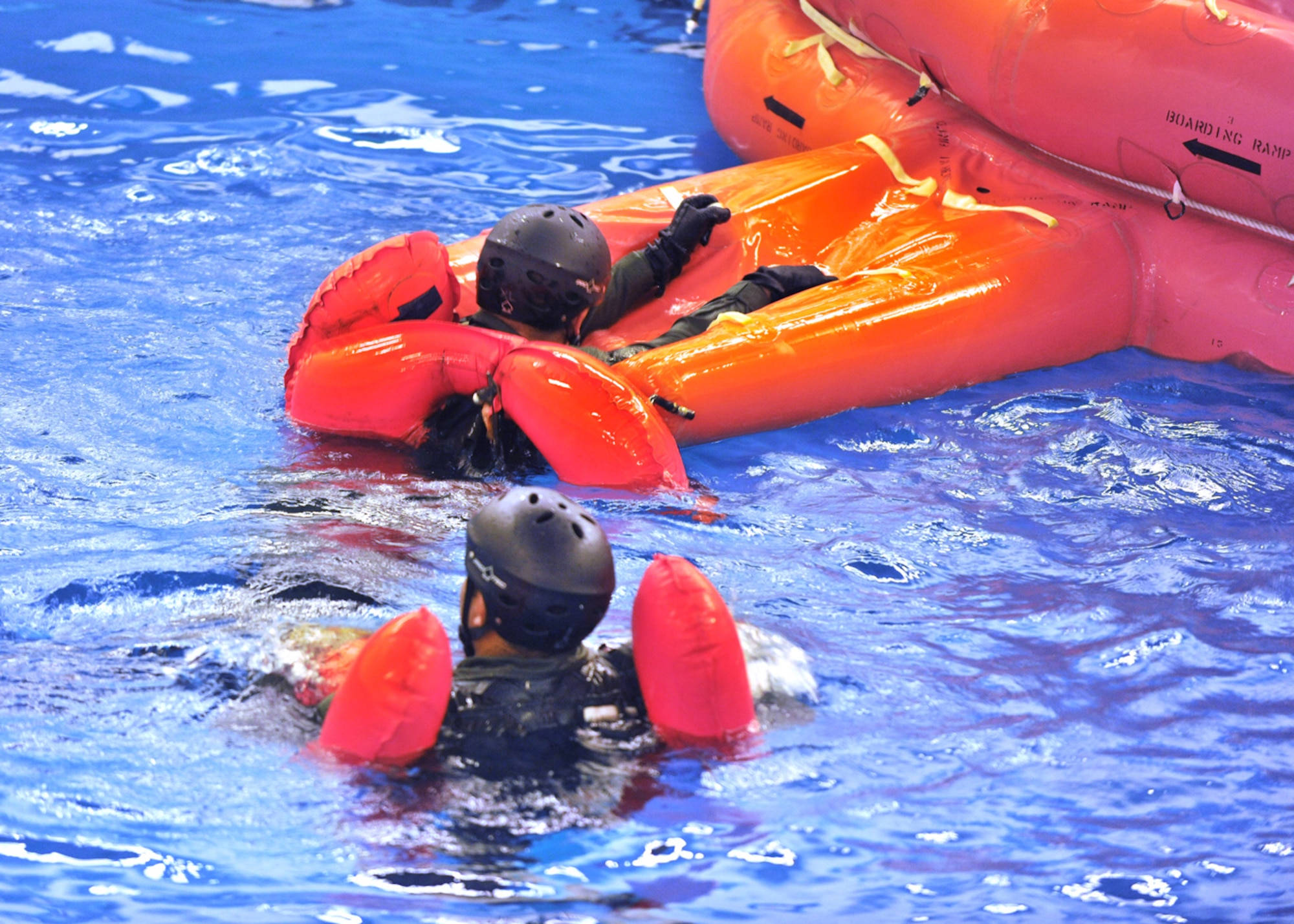 LOWESTOFT COLLEGE, England -- Aircrew members from RAFs Mildenhall and Lakenheath pull themselves onto a 20-man life raft July 14, 2011, which was part of the water survival training they have to attend. The pool  is 16-feet-deep, half-Olympic size and has pumps that create six- to eight-foot waves, fans which produce a 30-knot wind, and sprinkler system and lighting controls to replicate horrific sea conditions. (U.S. Air Force photo/Staff Sgt. Tabitha Lee)