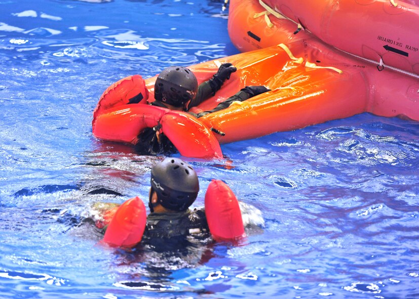 LOWESTOFT COLLEGE, England -- Aircrew members from RAFs Mildenhall and Lakenheath pull themselves onto a 20-man life raft July 14, 2011, which was part of the water survival training they have to attend. The pool  is 16-feet-deep, half-Olympic size and has pumps that create six- to eight-foot waves, fans which produce a 30-knot wind, and sprinkler system and lighting controls to replicate horrific sea conditions. (U.S. Air Force photo/Staff Sgt. Tabitha Lee)