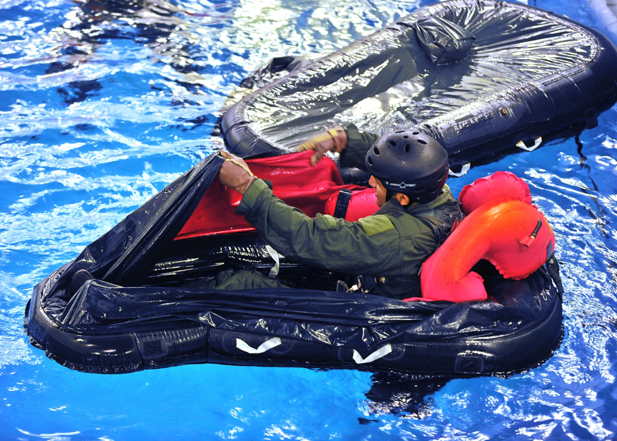 LOWESTOFT COLLEGE, England -- Once inside a single-man life raft, a U.S. Air Force aircrew member uses one of the side flaps to get rid of the water inside it July 14, 2011. Once the training in the small life raft is complete, all the aircrew swim to a 20-man life raft and pull themselves inside for the next stage of the training. (U.S. Air Force photo/Staff Sgt. Tabitha Lee)