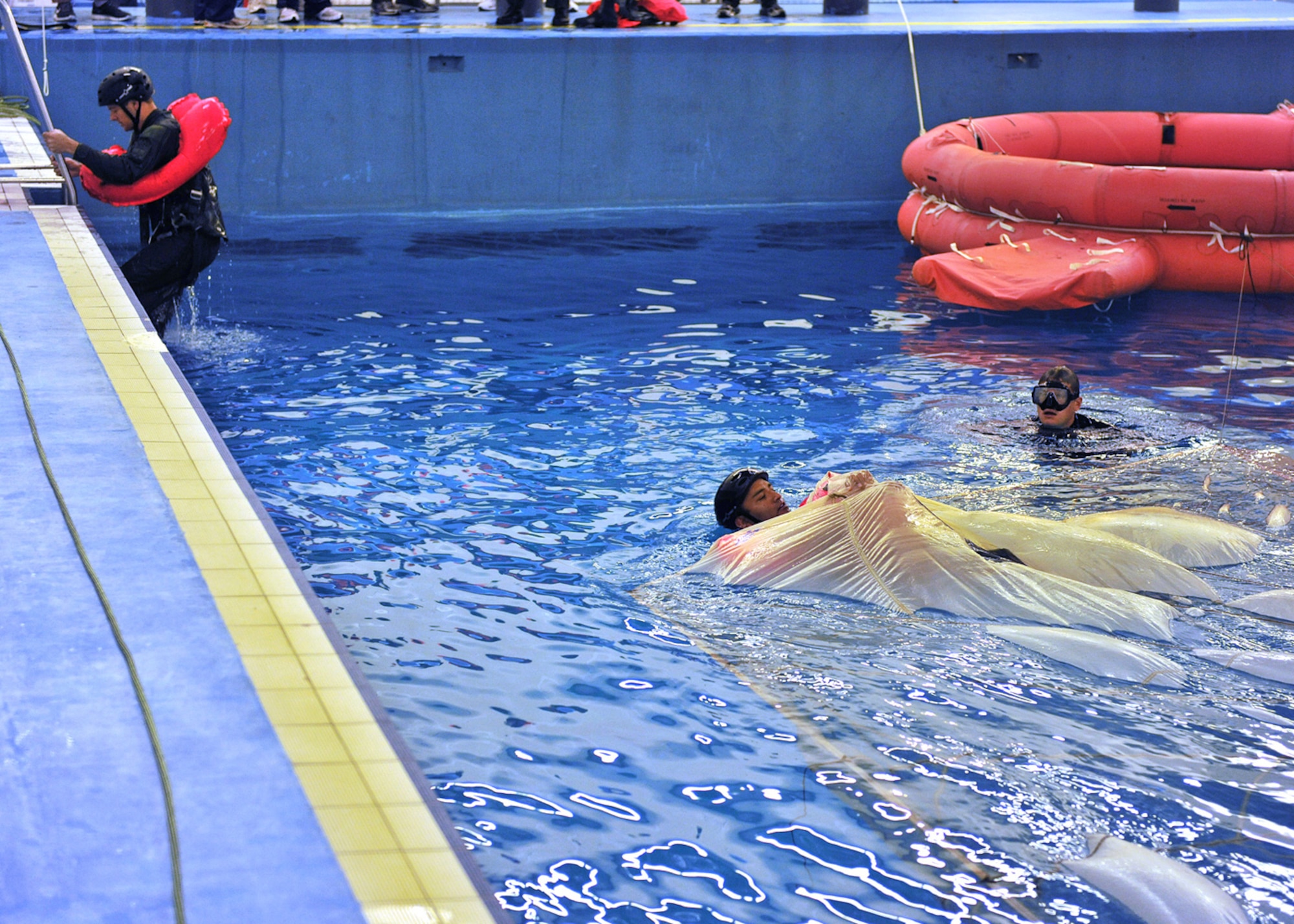LOWESTOFT COLLEGE, England -- U.S. Air Force members pull themselves along and underneath a parachute, which has been placed on top of the water in a 16-foot-deep pool, before climbing out of the pool, during water survival training July 14, 2011. (U.S. Air Force photo/Staff Sgt. Tabitha Lee)