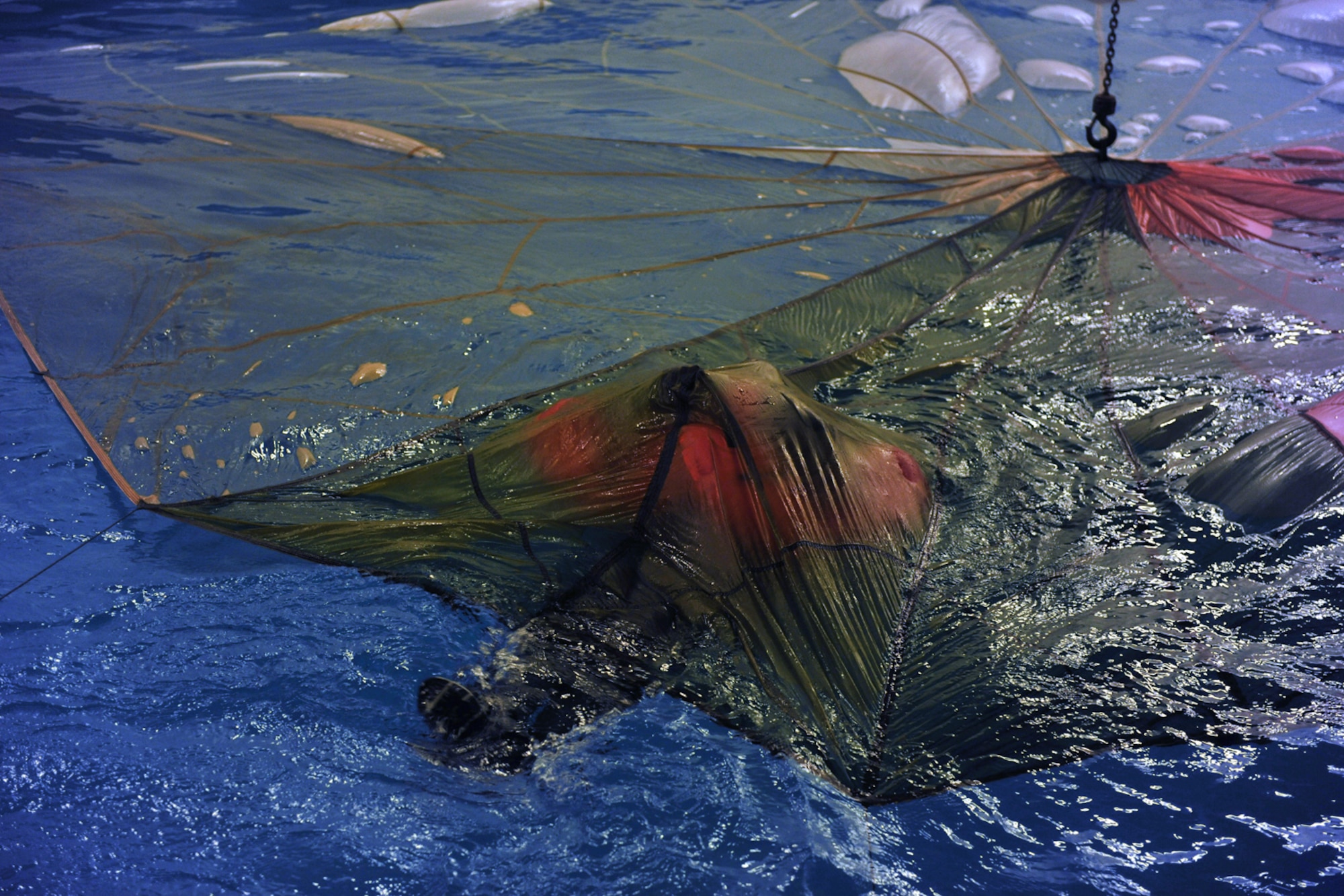 LOWESTOFT COLLEGE, England -- A U.S. Air Force aircrew member pulls himself along on his back underneath a parachute in the special-purpose pool at Lowestoft College July 14, 2011. The water survival portion of survival, evasion, resistance and escape training provides aircrew with practical experience and helps them gain confidence with the vital tools they would have to use in a real-world situation. The parachute training is vital, as on evacuation from an aircraft, if the parachute lands on the survivor in the water, it could drown him or her if the life preserver isn't inflated and that person doesn't know how to get untangled from the parachute. (U.S. Air Force photo/Staff Sgt. Tabitha Lee)