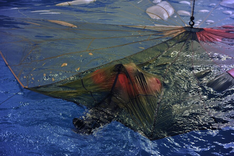 LOWESTOFT COLLEGE, England -- A U.S. Air Force aircrew member pulls himself along on his back underneath a parachute in the special-purpose pool at Lowestoft College July 14, 2011. The water survival portion of survival, evasion, resistance and escape training provides aircrew with practical experience and helps them gain confidence with the vital tools they would have to use in a real-world situation. The parachute training is vital, as on evacuation from an aircraft, if the parachute lands on the survivor in the water, it could drown him or her if the life preserver isn't inflated and that person doesn't know how to get untangled from the parachute. (U.S. Air Force photo/Staff Sgt. Tabitha Lee)