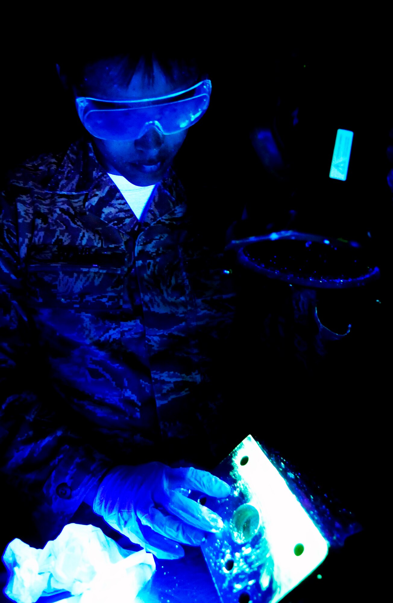 RAF MILDENHALL, England -- Senior Airman Christopher Bovill, 100th Maintenance Squadron Non-Destructive Inspection journeyman, shines a black light onto a KC-135 Stratotanker jack-mount during a fluorescent liquid penetrant inspection July 28, 2011. The black light is used to determine where the cracks in the landing gear are by making the florescent dye penetrant that resides in the cracks glow. (U.S. Air Force photo/Senior Airman Ethan Morgan)