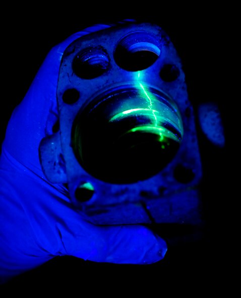 RAF MILDENHALL, England -- The nose landing gear hydraulic sub-assembly from a KC-135 Stratotanker is examined under a black light during a fluorescent liquid penetrant inspection July 28, 2011. The black light allows any cracks that may be in the landing gear to be highlighted, showing the exact location of the damage. (U.S. Air Force photo/Senior Airman Ethan Morgan)