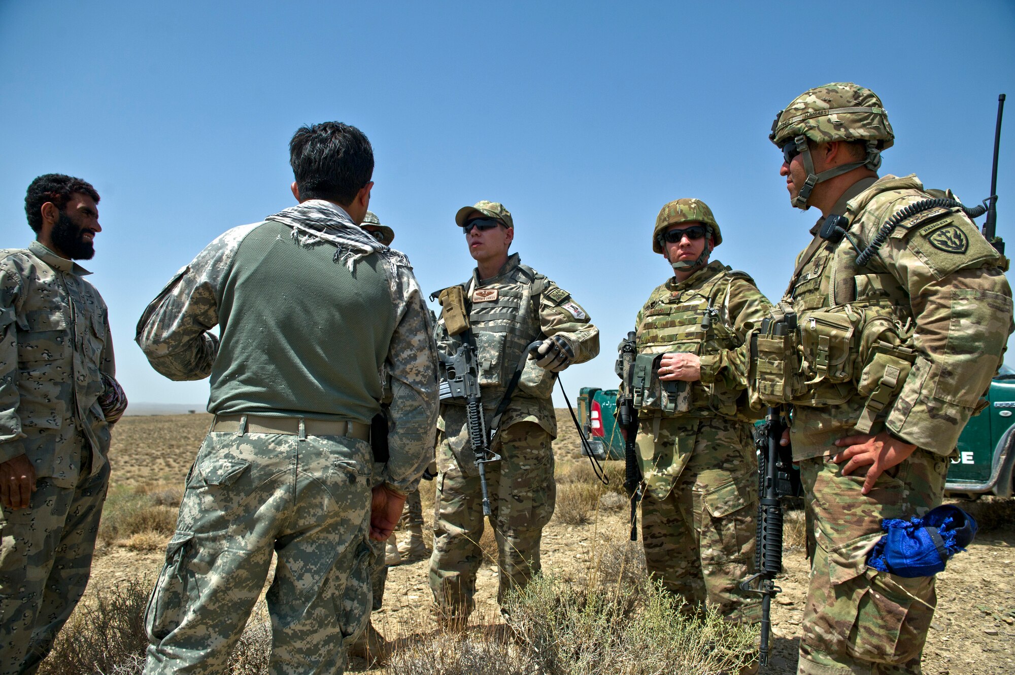 U.S. Air Force Capt. Matthew Zahler and Maj. Jason Helton, air mobility liaison officers, uses a translator to talk to Afghanistan border police about the best location to establish a drop zone near their remote compound in southern Afghanistan. Zahler relies on local knowledge of the area in order to avoid establishing the drop zone on old mine fields and areas used by Taliban fighters. (U.S. Air Force Photo/Master Sgt. Jeffrey Allen)