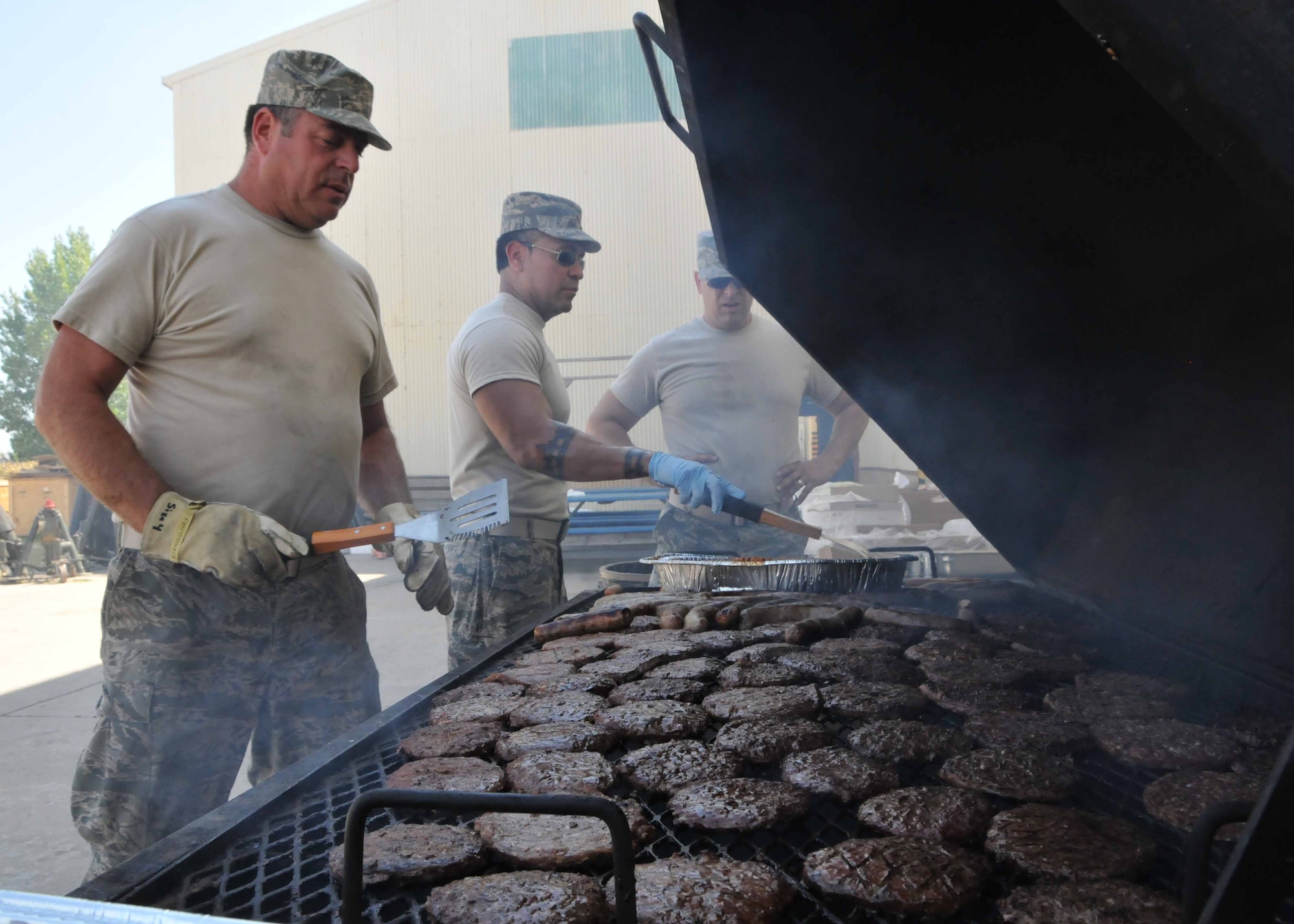 Master Sgt. Glenn T. Bosch (left), Maj. Jesse Ortega (middle), and Chief Master Sgt. Joseph A. Parlato work the grill for a senior enlisted leader sponsored burger burn at the 313th Air Expeditionary Wing on Thursday July 28, 2011 in Western Europe. (U.S. Air Force photo/Capt. John Capra)