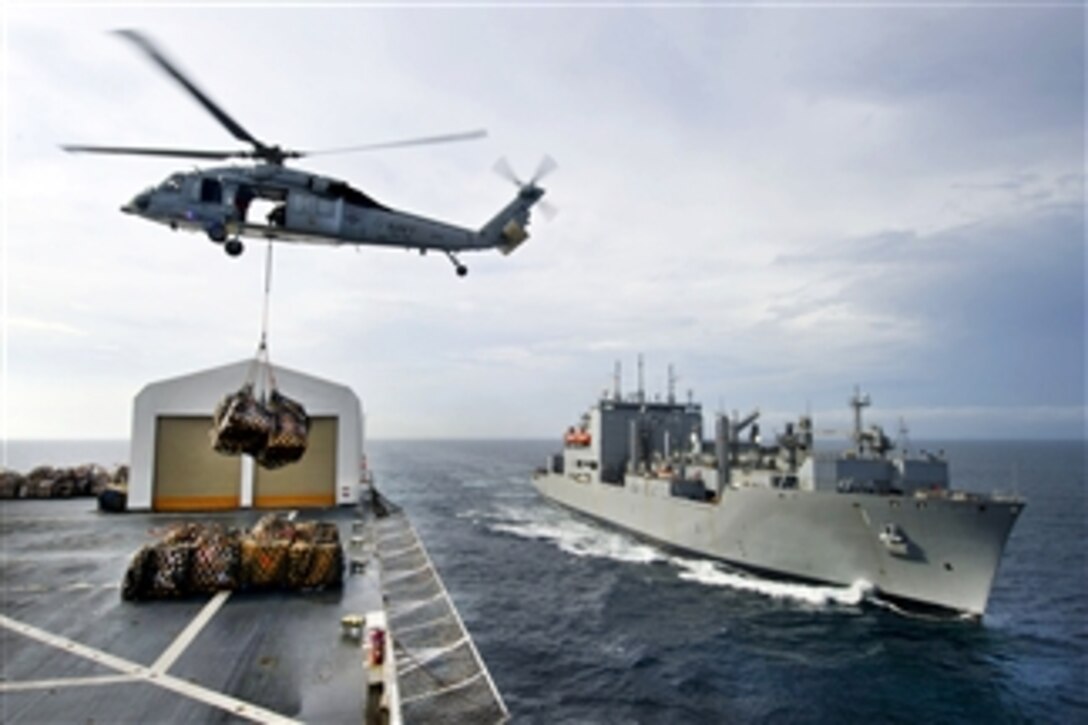 An MH-60S Knight Hawk helicopter transports cargo from the USNS Comfort to the USNS Lewis and Clark during a replenishment mission underway in the Pacific Ocean on July 26, 2011.  