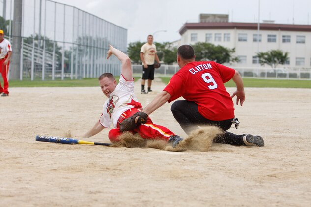 Roy L. Clayton Jr., Torii catcher, attempts to tag Peter A. Lawson, Iwakuni extra hitter, as he slides home during the semi finals of the 2011 One-Pitch Softball Tournament here July 29. Iwakuni beat Torii during the championship game 10-9.