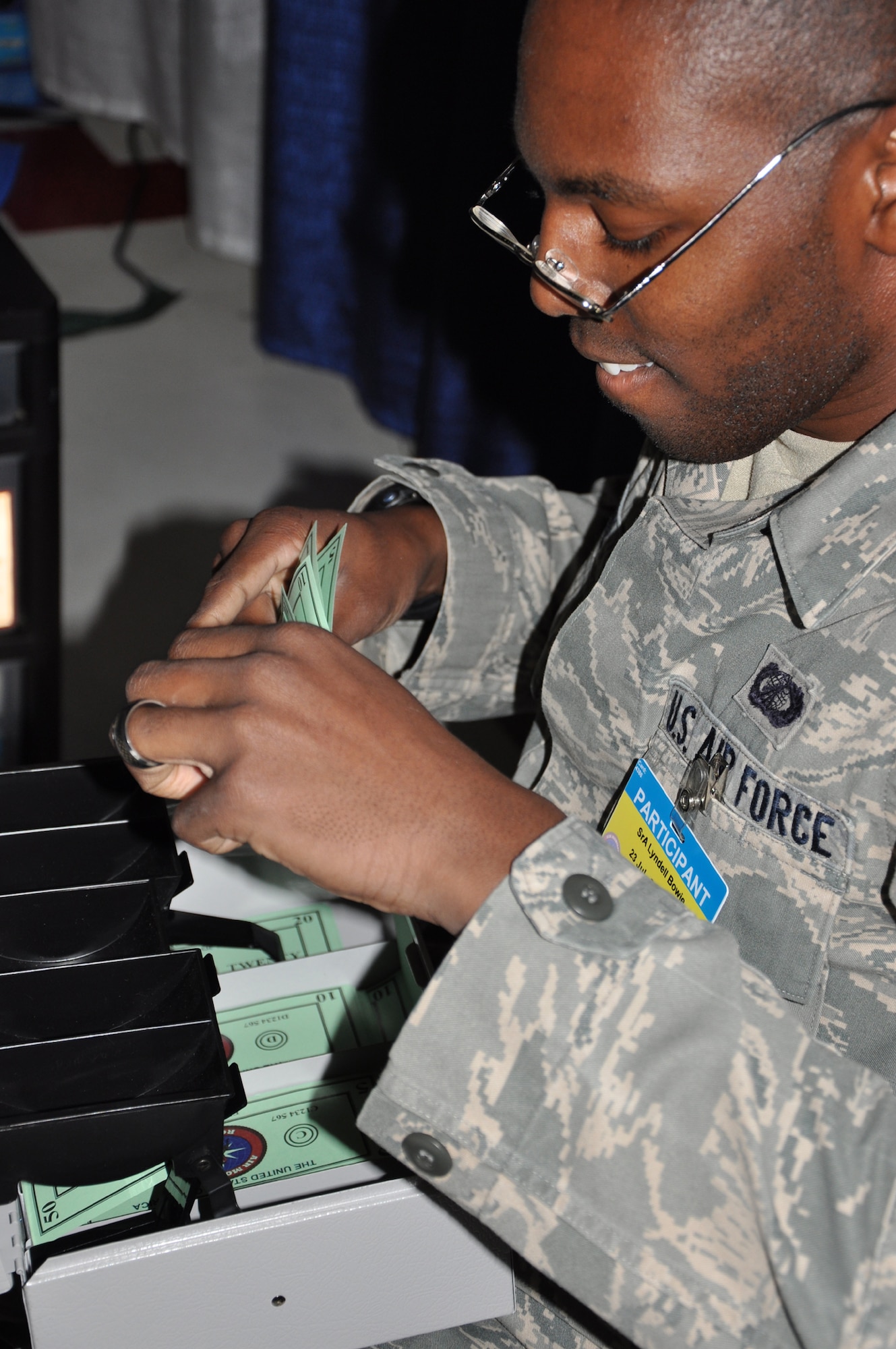 Senior Airman Lyndell Bowie, 92nd Comptroller Squadron, counts simulated money in the simulated deployed environment behind curtains in Joint Base Lewis-McChord's Hangar 2, Wash., July 28 as part of the Air Mobility Rodeo. The finance specialists worked 155 scenarios in four days as part of their competition. (U.S. Air Force Photo/Tech. Sgt. Jennifer Buzanowski)