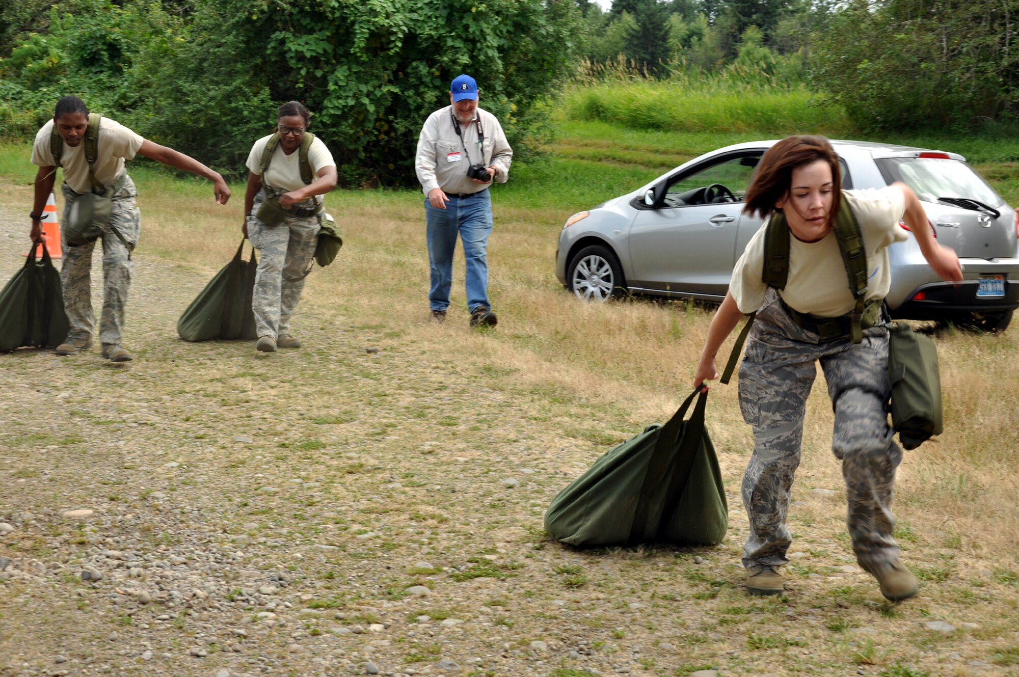 Staff Sgt. Christie Bates leads her teammates Senior Airman Lyndell Bowie and Tech. Sgt. Adrienne Johnson as they drag a simulated $1.6 million as part of their challenge course July 26. Dennis Clay, civic leader from Moses Lake, cheers on the team during this Air Mobility Rode event at Joint Base Lewis-McChord, Wash. (U.S. Air Force Photo/Tech. Sgt. Jennifer Buzanowski)