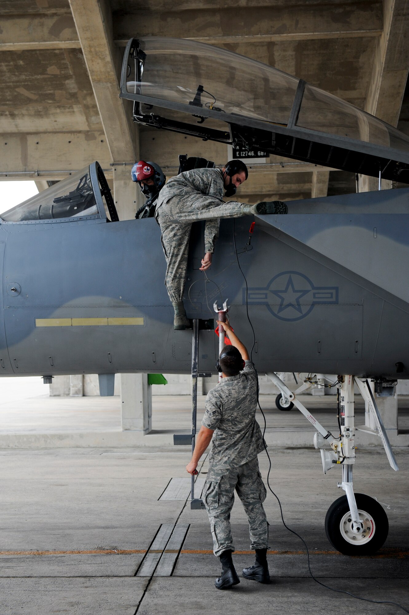 Airman 1st Class Cody Kuhs hands down the cockpit brace to Airman 1st Class Eric Smith while Brig. Gen. Ken Wilsbach, 18th Wing commander, prepares his F-15 Eagle for his final flight as the wing commander June 1. Following a change of command ceremony June 3, General Wilsbach will leave Kadena to become the United States Pacific Command deputy director for operations . Airman Kuhs and Airman Smith are both from the 67th Aircraft Maintenance Unit here. (U.S. Air Force photo/Staff Sgt. Jonathan Steffen)