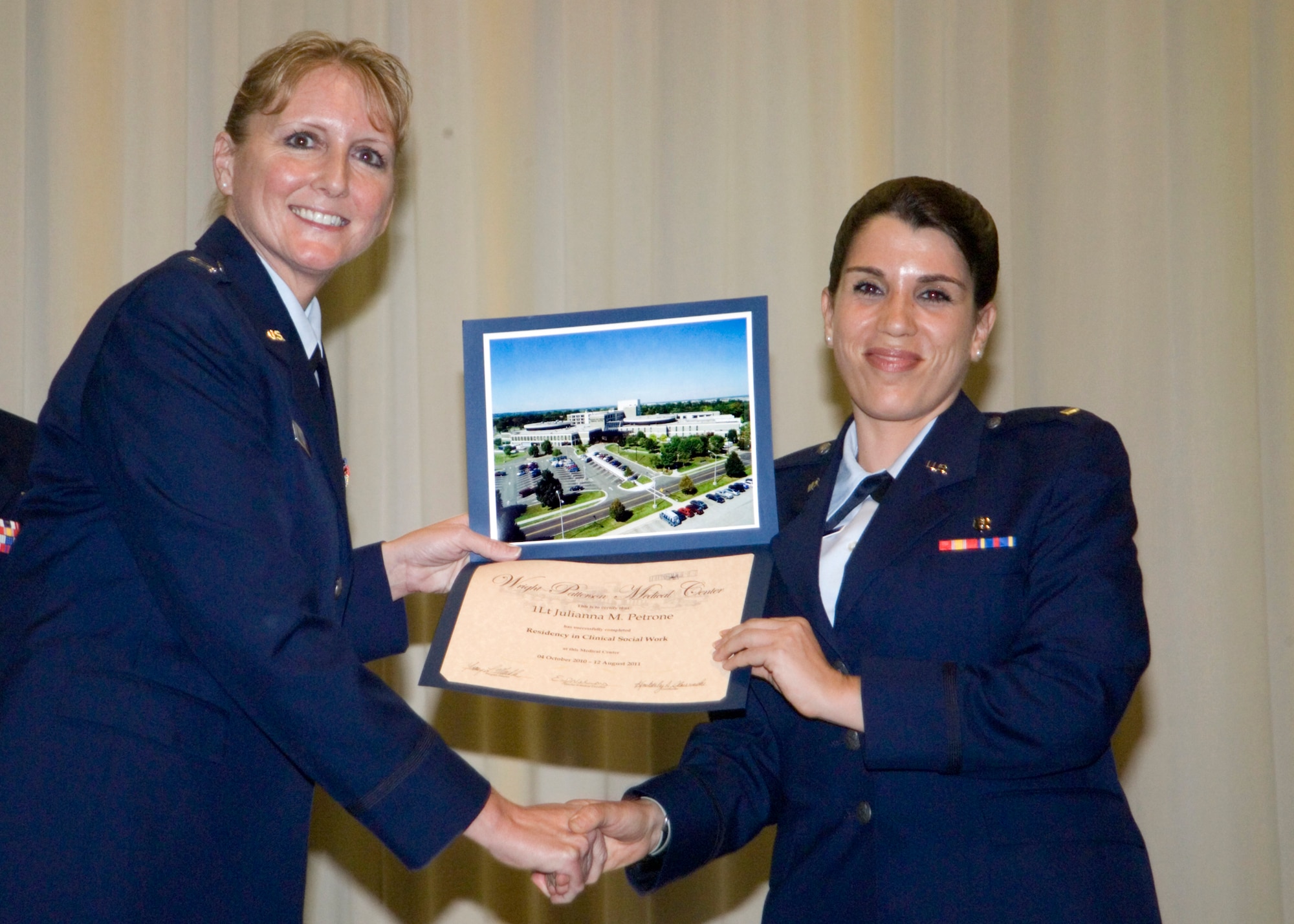 Capt Tracy Markle presents diploma to 1st Lt. Julianna Petrone during the graduation ceremony for Wright-Patterson Medical Center medical and dental education residents held May 26, 2011 at the National Museum of the U.S. Air Force. Captain Markle is internship program director for Social Work.  Lieutenant Petrone is a clinical social worker who will be assigned to Keelser Air Force Base, Miss. (U.S. Air Force photo/Mark Pugel) 