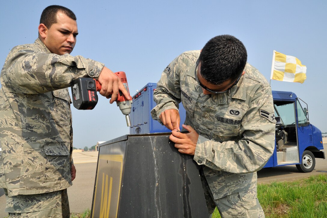 Senior Airmen Victor Gonzalez-Diaz,  11th Civil Engineer Squadron electrical systems journeyman, and Airman 1st Class Erick Rodriguez, 11th CES electrical systems apprentice, replace the case of a taxiway location sign after replacing the lights and adjusting the brightness June 1, 2011 at Joint Base Andrews, Md. The Airmen of 11th CES airfield lighting maintain all the lights and their electrical systems on the flightline. (U.S. Air Force photo/Senior Airman Perry Aston) 