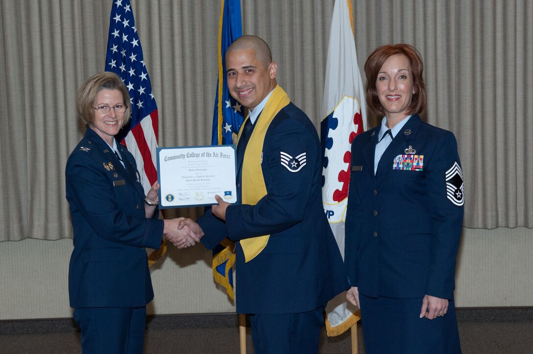 Staff Sgt. Andre Olaciregui (middle) accepts his Community College of the Air Force degree from Col. Stacy L. Yike (left), 66th Air Base Group commander, during the CCAF graduation in the Hanscom Conference Center May 5. Chief Master Sgt. Laura Noel (right), Electronic Systems Center interim command chief, provided the commencement address to the 20 Airmen receiving degrees. (U.S. Air Force photo/Rick Berry)