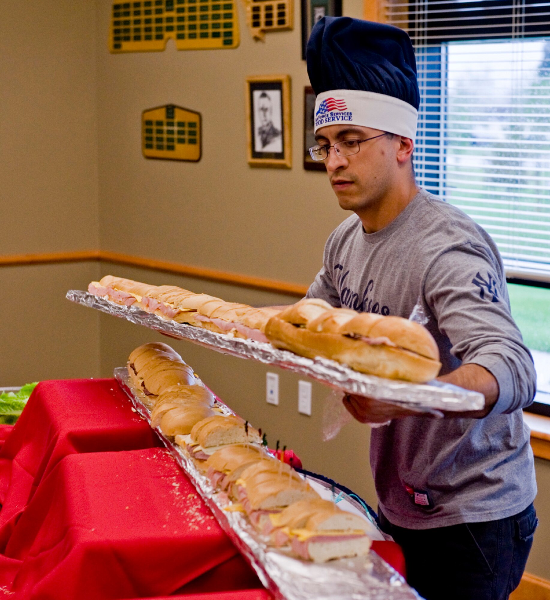 Senior Airman Josue Silva, a 341st Force Support Squadron food services specialist, places a tray of sandwiches in one of the community activity center’s conference rooms. Guests at the grand opening consumed 10, 6-foot subs. (U.S. Air Force photo/John Turner)