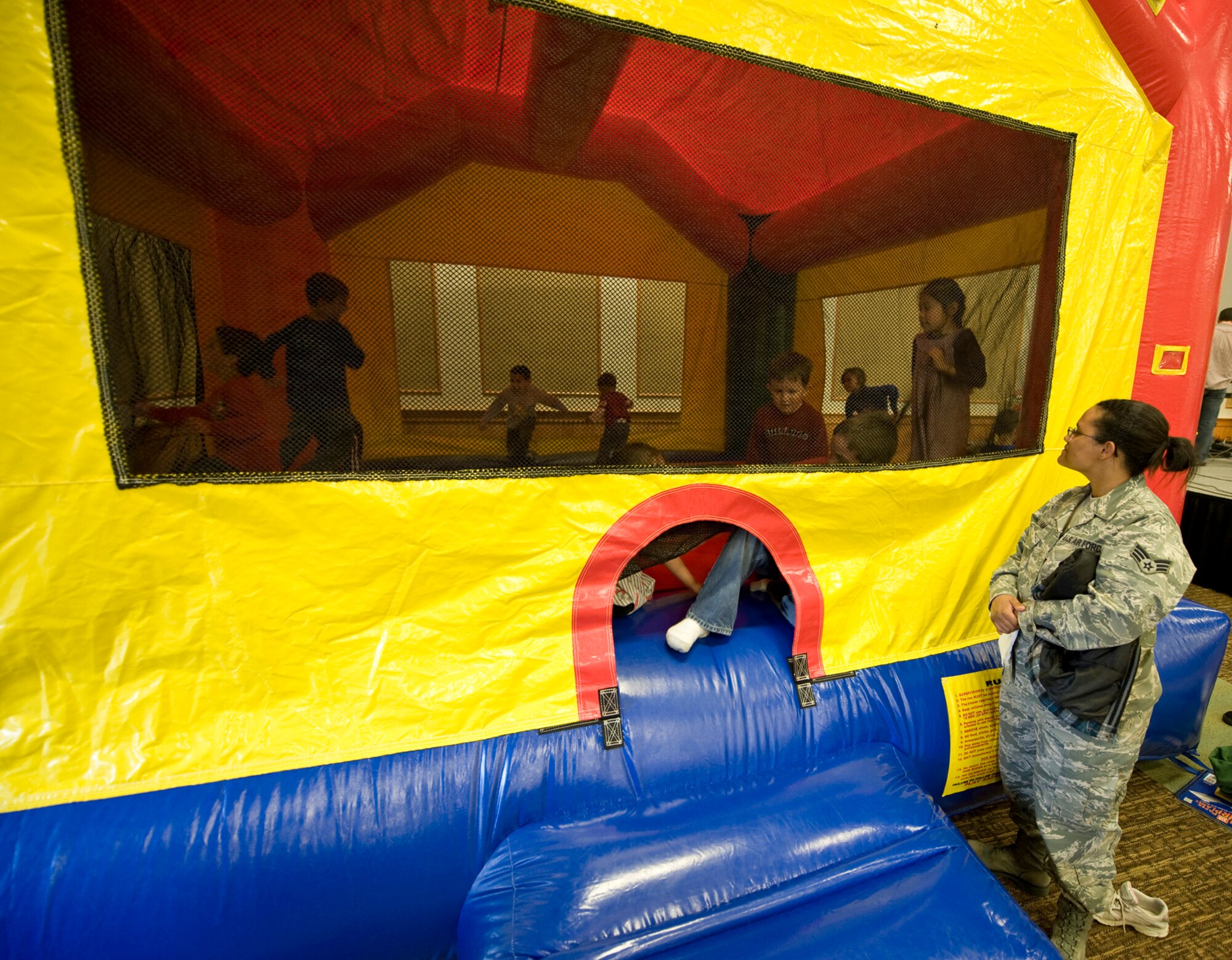 Senior Airman Shaleena Pulliam, 341st Medical Operations Squadron, watches as her son, Kai, and other children hop around in an inflated bouncy castle. (U.S. Air Force photo/John Turner)