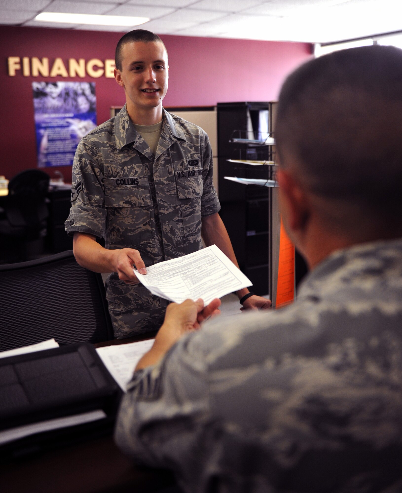 Airman 1st Class Alex Collins, a 19th Comptroller Squadron lead counter technician, receives important financial documents from a customer May 31, 2011, at Little Rock Air Force Base, Ark. The Tawas, Mich., native is a designated driver volunteer and has led a community cleanup effort for the 19th Airlift Wing’s Director of Staff agencies. (U.S. Air Force photo/Airman 1st Class Rusty Frank)