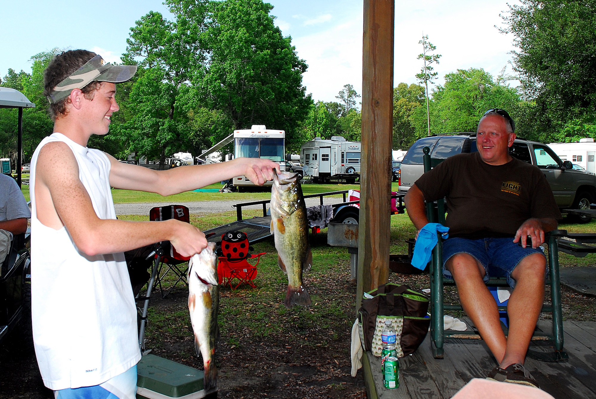 Fifteen-year-old Tyler Mills proudly shows Tech Sgt. Ron Morris two largemouth bass he caught while fishing in Lake Moultrie at Short Stay Navy Outdoor Recreation area near Moncks Corner, S.C., May 28.  Short Stay offers fishing, camping and boating for patrons. (U.S. Navy photo/Machinist's Mate 3rd Class Brannon Deugan)
