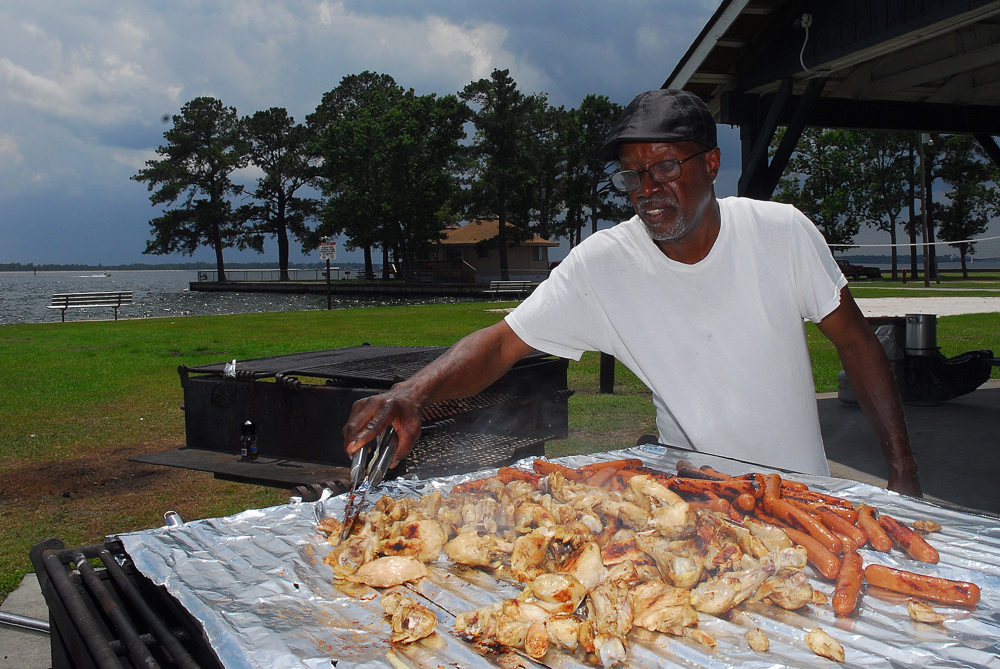 Julius Middleton, from Hollyhill, S.C., grills chicken and hotdogs for a family gathering during the Memorial Day weekend at Short Stay Navy Outdoor Recreation area on Lake Moultrie near Moncks Corner, S.C., May 28. Mr. Middleton was spending time with his family and son, Yeoman Chief Petty Officer Travar Middleton who is stationed at the Office of Chief of Navy Reserve in Washington, D.C., and was visiting during the holiday weekend.  (U.S. Navy photo/Machinist's Mate 3rd Class Brannon Deugan)
