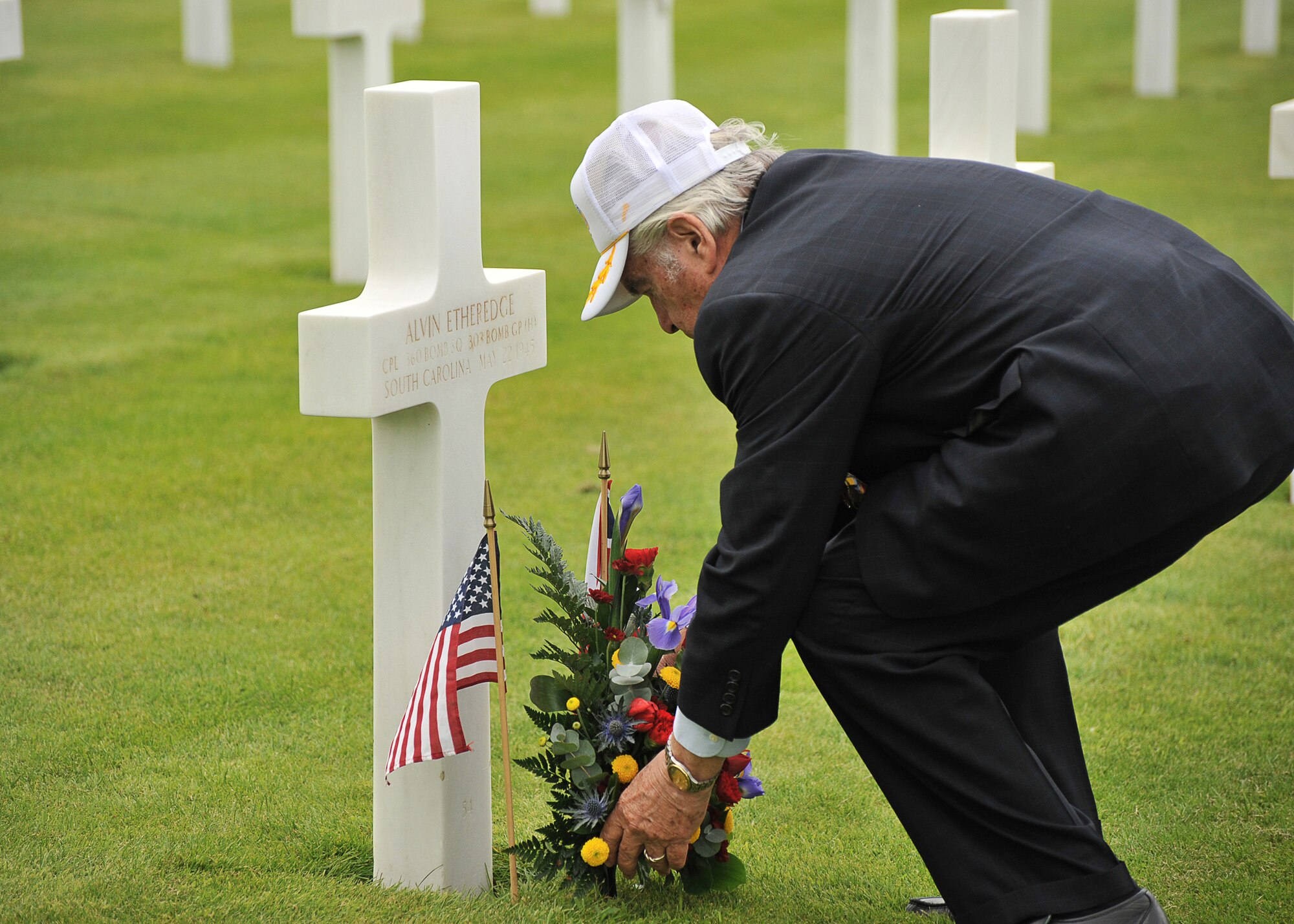 303rd Bomb Group veteran Eddie Deerfield lays a floral spray at the grave of his crewman right waist gunner Cpl.  Alvin Etheredge.  Etheredge was removed from flight status in August 1943 after flying 13 missions and served on the MSgt Robert B. Heiliger ground crew until he died from a tumor in May 1945 (U.S. Air Force photo by Staff Sgt. Javier Cruz)