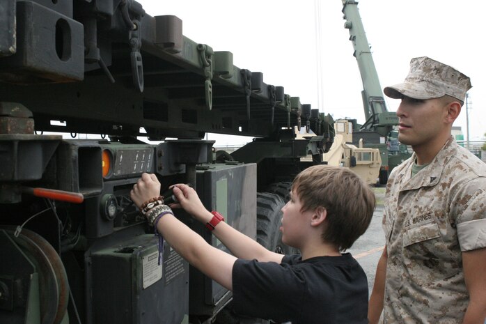 Ryan C. Archameault, 12, a Matthew C. Perry High School seventh-grader, operates the flat bed of a MK-48/18A1 while Lance Cpl. Horacio Vieyra, a Marine Wing Support Squadron 171 logistics vehicle operator, goes over some of the safety::r::::n::procedures as part of the Advancement Via Individual Determination program next to the IronWorks Gym here June 1. The AVID program offers students an opportunity to consider their options for the future, including joining the Marine Corps.